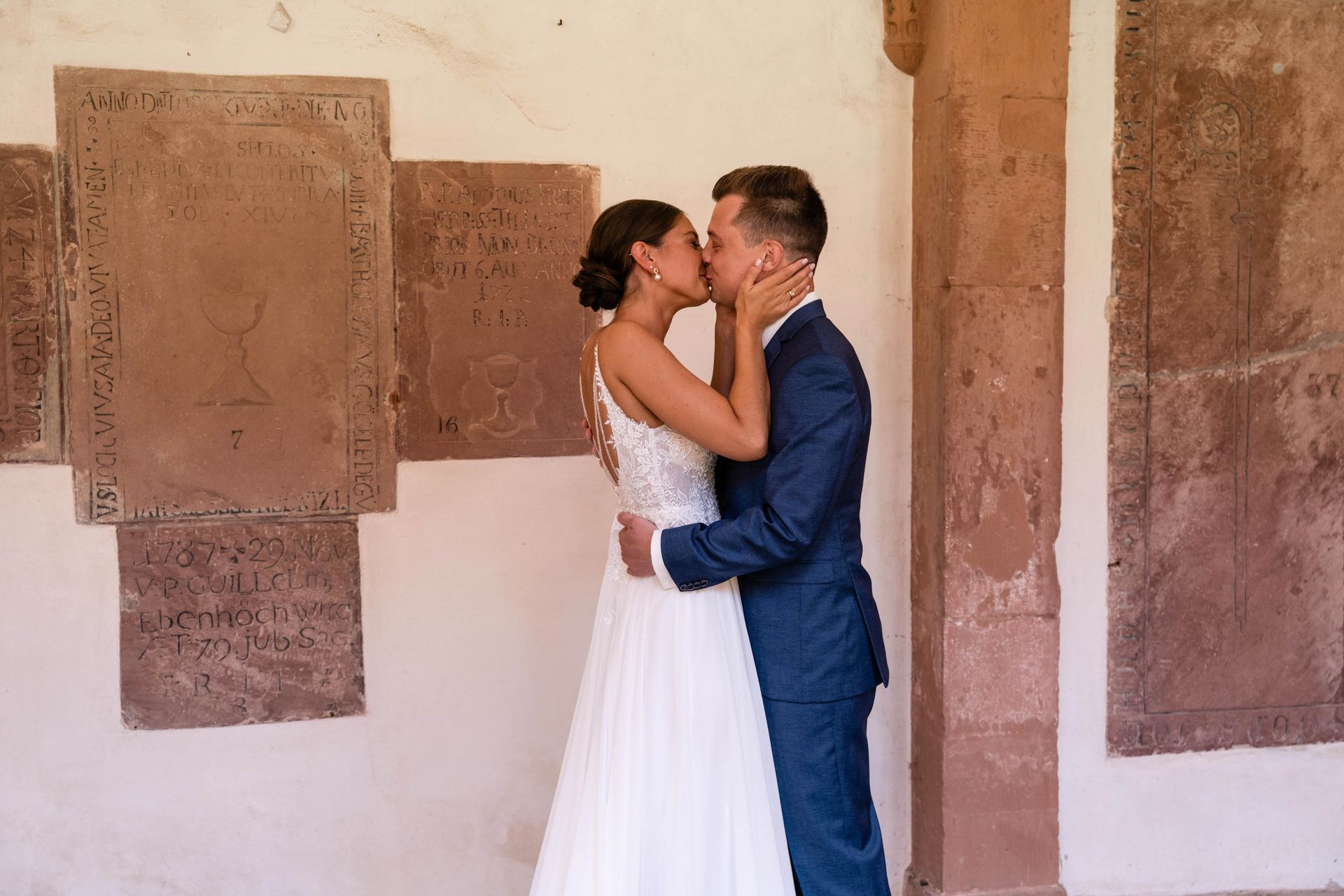 First Look im Kreuzgang Kloster Bronnbach, Braut und Bräutigam küssen sich.