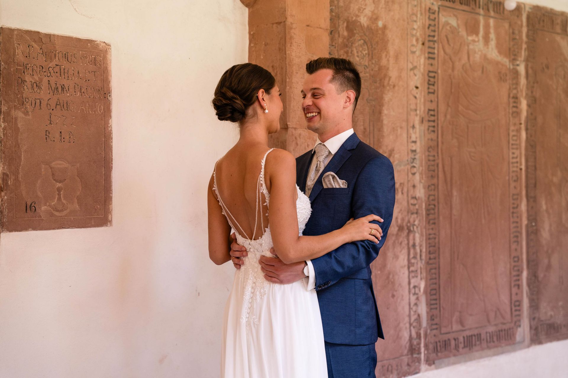 First Look im Kreuzgang Kloster Bronnbach, Braut und Bräutigam lachen sich an.