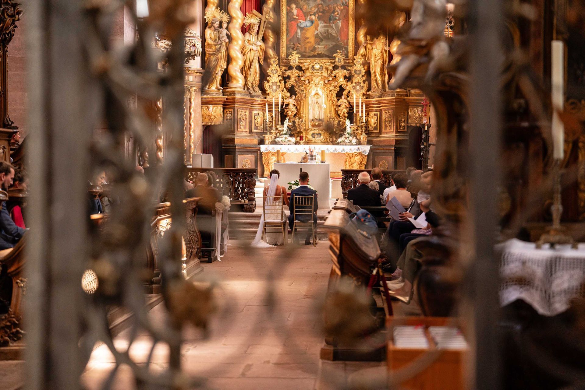 Klosterkirche im Kloster Bronnbach kirchliche Trauung, Brautpaar sitz vor dem Altar. Aufnahme von der Ferne.