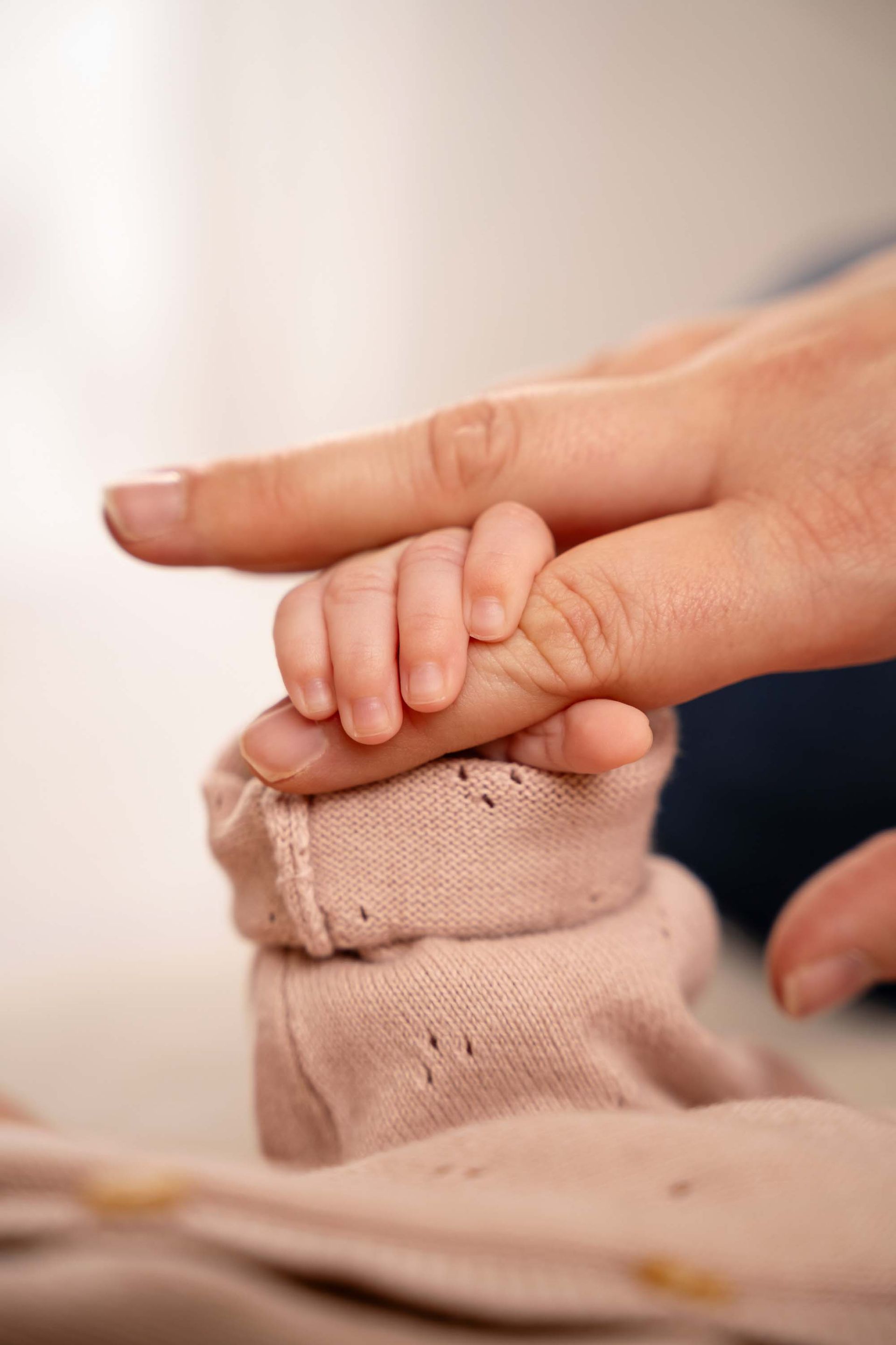 Nahaufnahme einer erwachsenen Fingerkuppe, die sanft den Finger eines Babys berührt