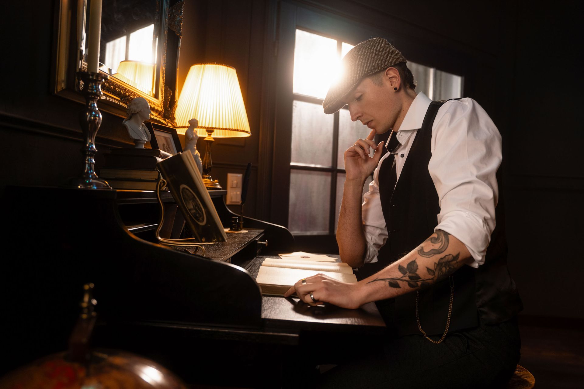Mann im Vintage-Stil mit Schiebermütze und Weste sitzt nachdenklich am Klavier in einem dunklen Raum