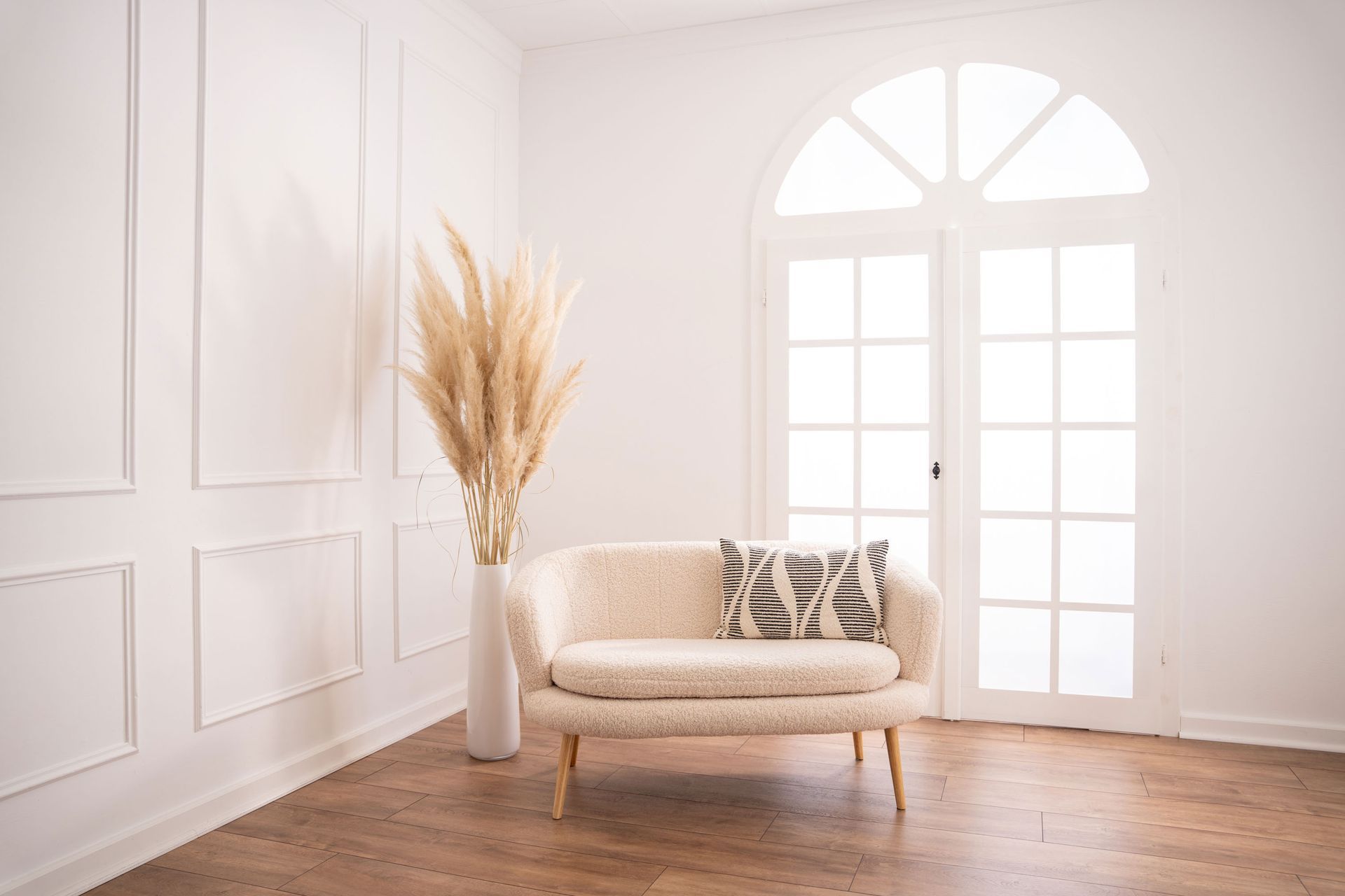 Mietstudio weißer Raum Studio zum mieten für Cosplay Fotografie. Großes weißes beleuchtetes Fenster bei weißer Barockwand mit Sofa und Pampasgras.