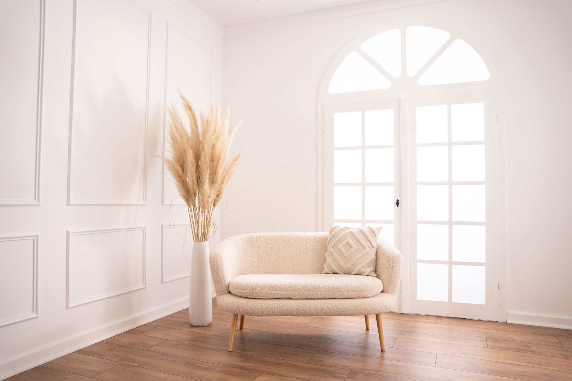 Mietstudio weißer Raum Studio zum mieten für Cosplay Fotografie. Großes weißes beleuchtetes Fenster bei weißer Barockwand mit Sofa und Pampasgras.