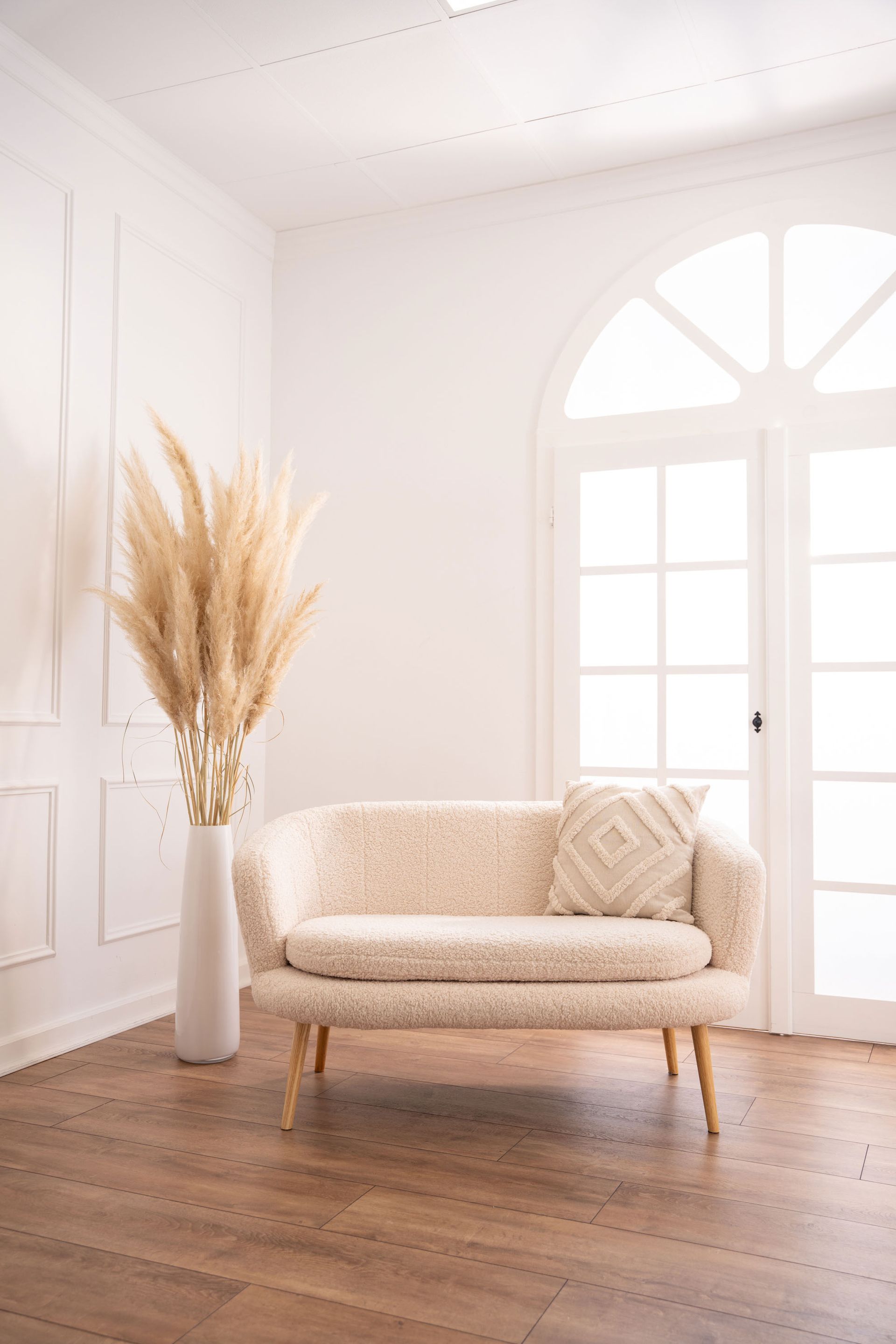 Mietstudio weißer Raum Studio zum mieten für Cosplay Fotografie. Großes weißes beleuchtetes Fenster bei weißer Barockwand mit Sofa und Pampasgras.