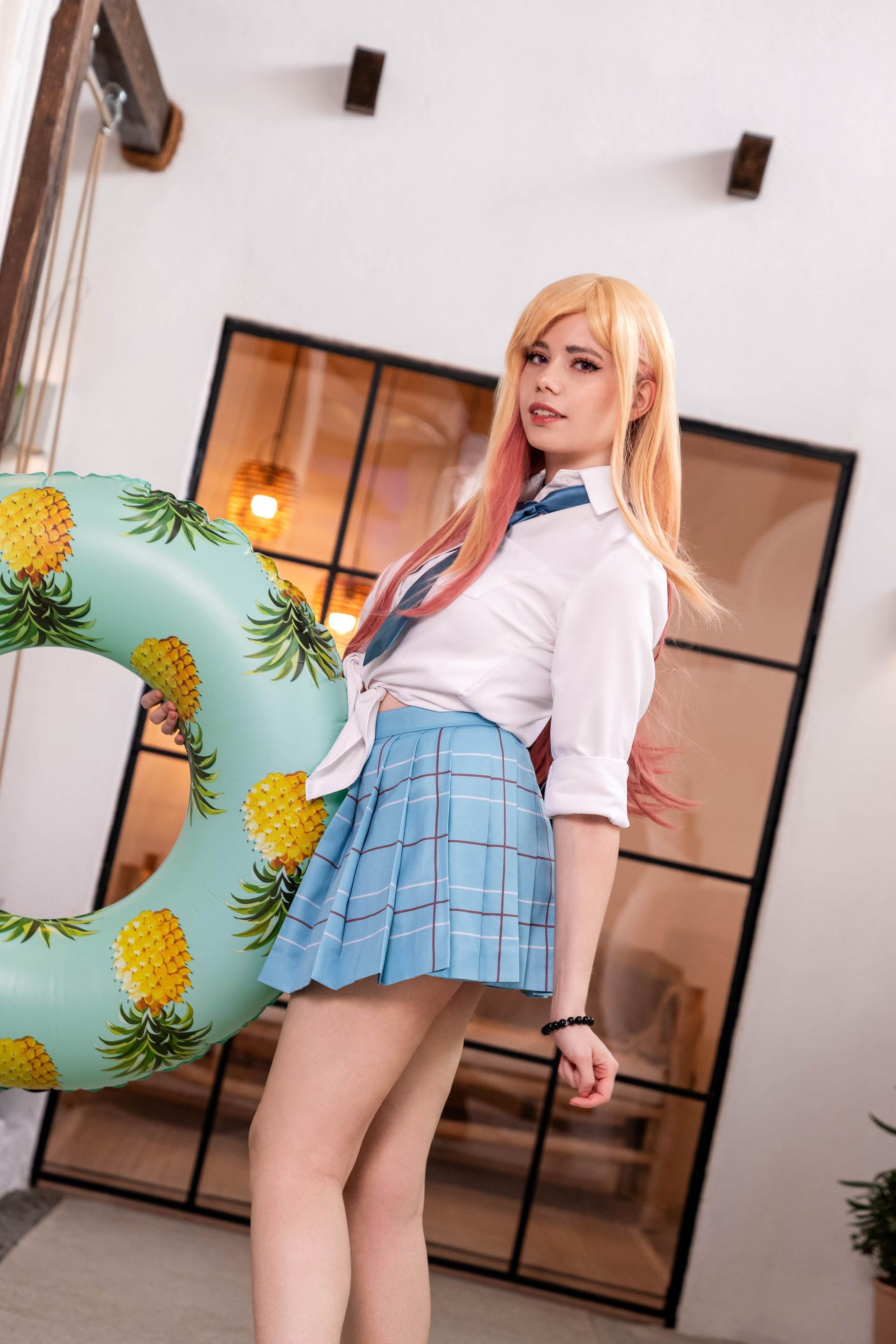 Blonde Cosplayerin in Schuluniform schaut in die Kamera in einem hellen modernen Innenraum