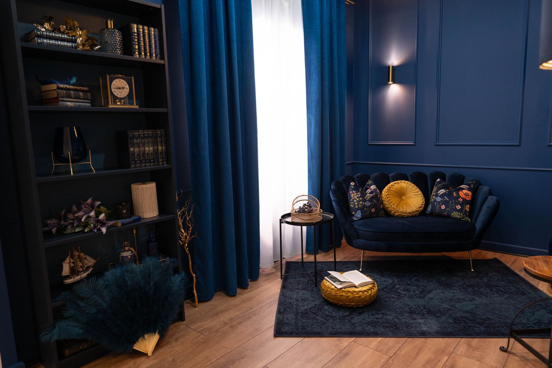 Blaues Wohnzimmer mit Bücherregal, Stehlampe und Samtsofa – warme und anspruchsvolle Atmosphäre für professionelle Fotos.