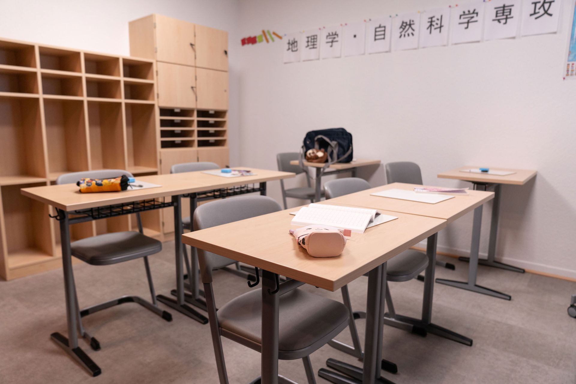 Seitliche Ansicht eines Klassenzimmers mit Schülertischen, Stühlen und Wandtafel mit chinesischen Schriftzeichen