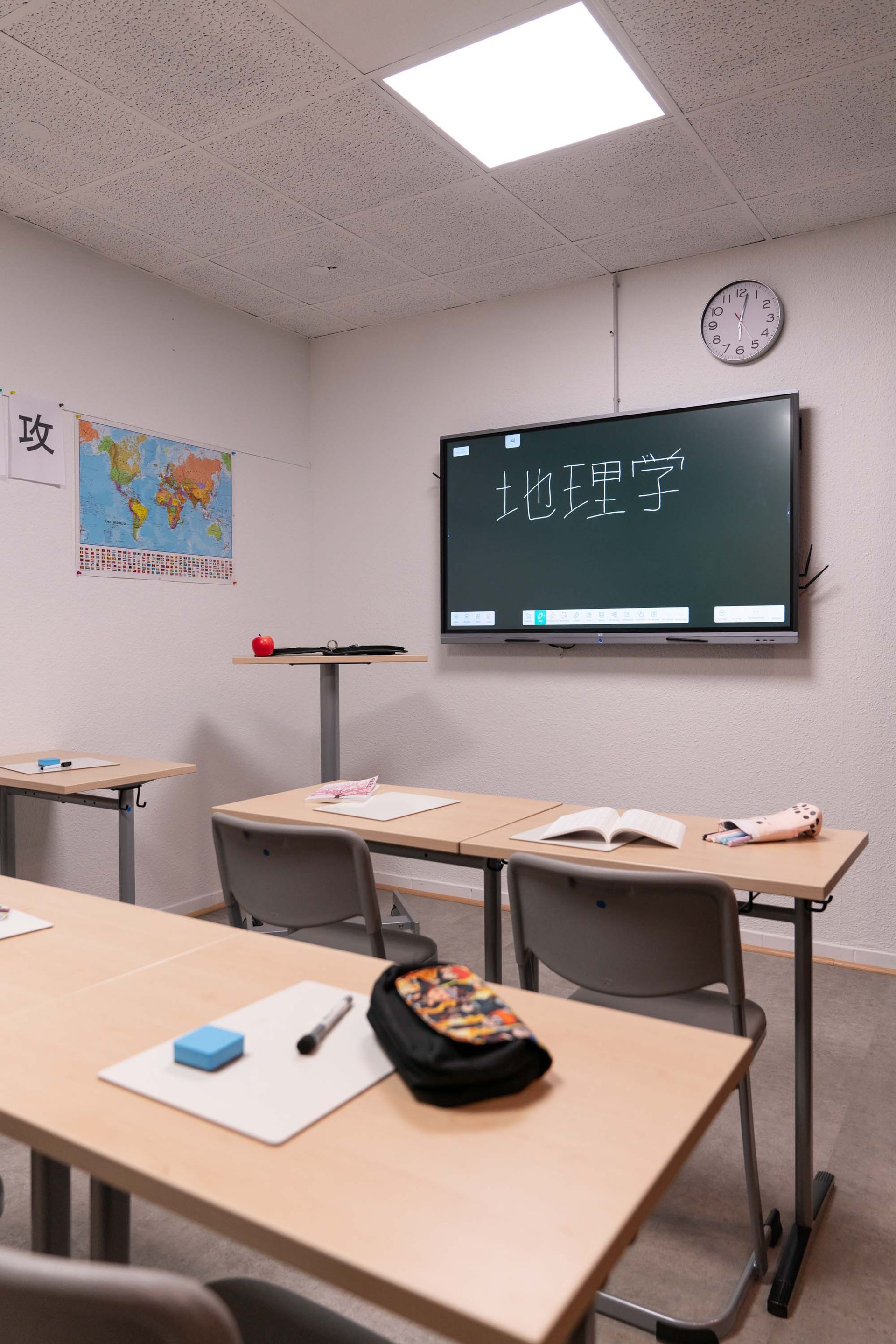 Realistisches Klassenzimmer mit Tafel, Weltkarte und einzelnen Schulbänken in moderner Einrichtung