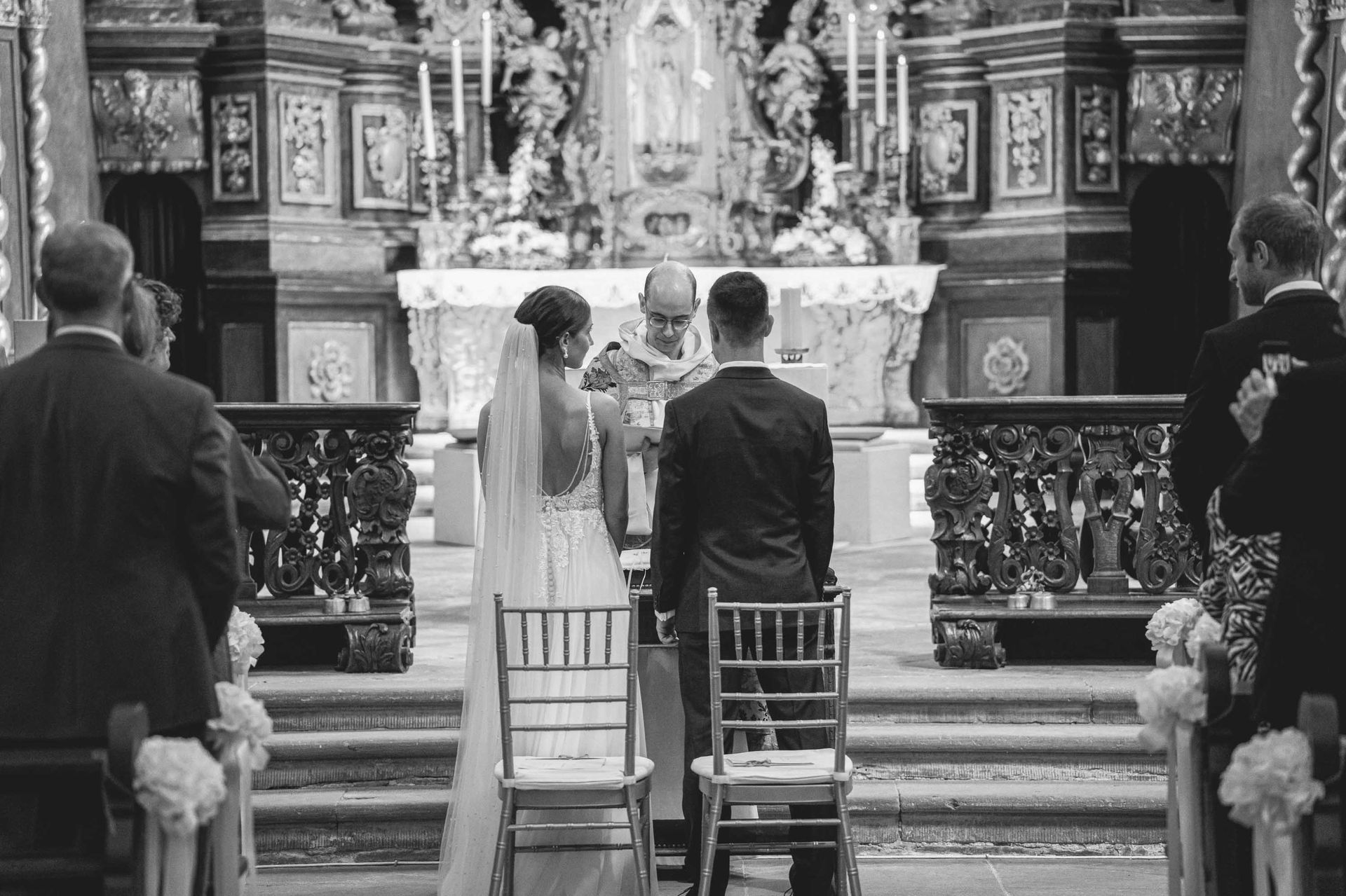Schwarz-weiß Foto, Klosterkirche im Kloster Bronnbach kirchliche Trauung, Brautpaar steht vor dem Altar und schauen zum Pfarrer.