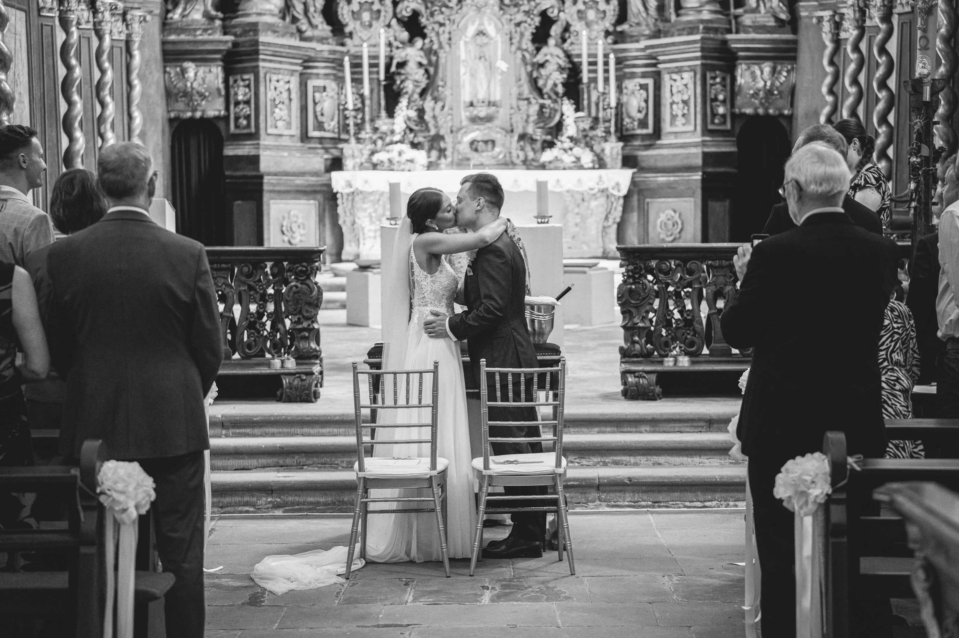 Schwarz-weiß Foto, Klosterkirche im Kloster Bronnbach kirchliche Trauung, Brautpaar küsst sich.