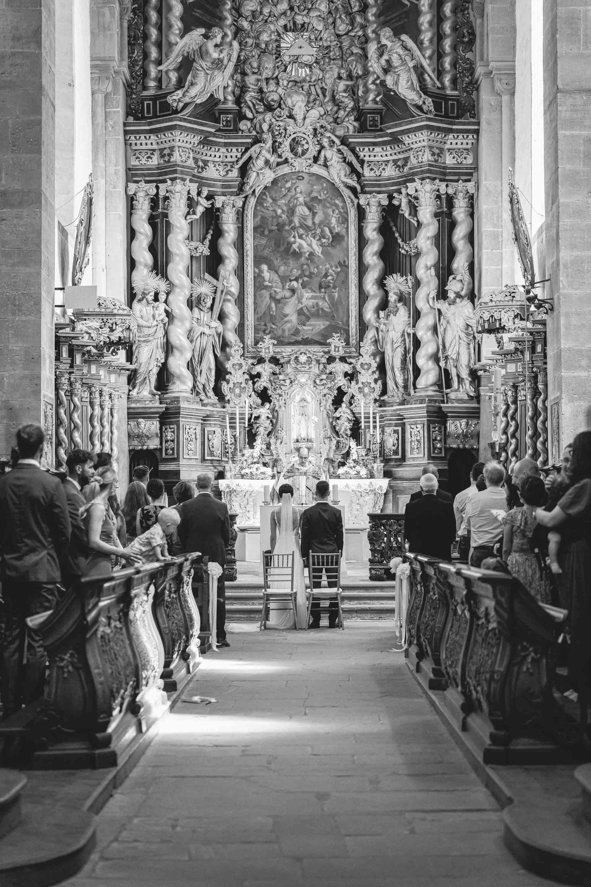 Schwarz-weiß Foto Klosterkirche im Kloster Bronnbach kirchliche Trauung, Brautpaar steht vor dem Altar. Aufnahme von der Ferne.
