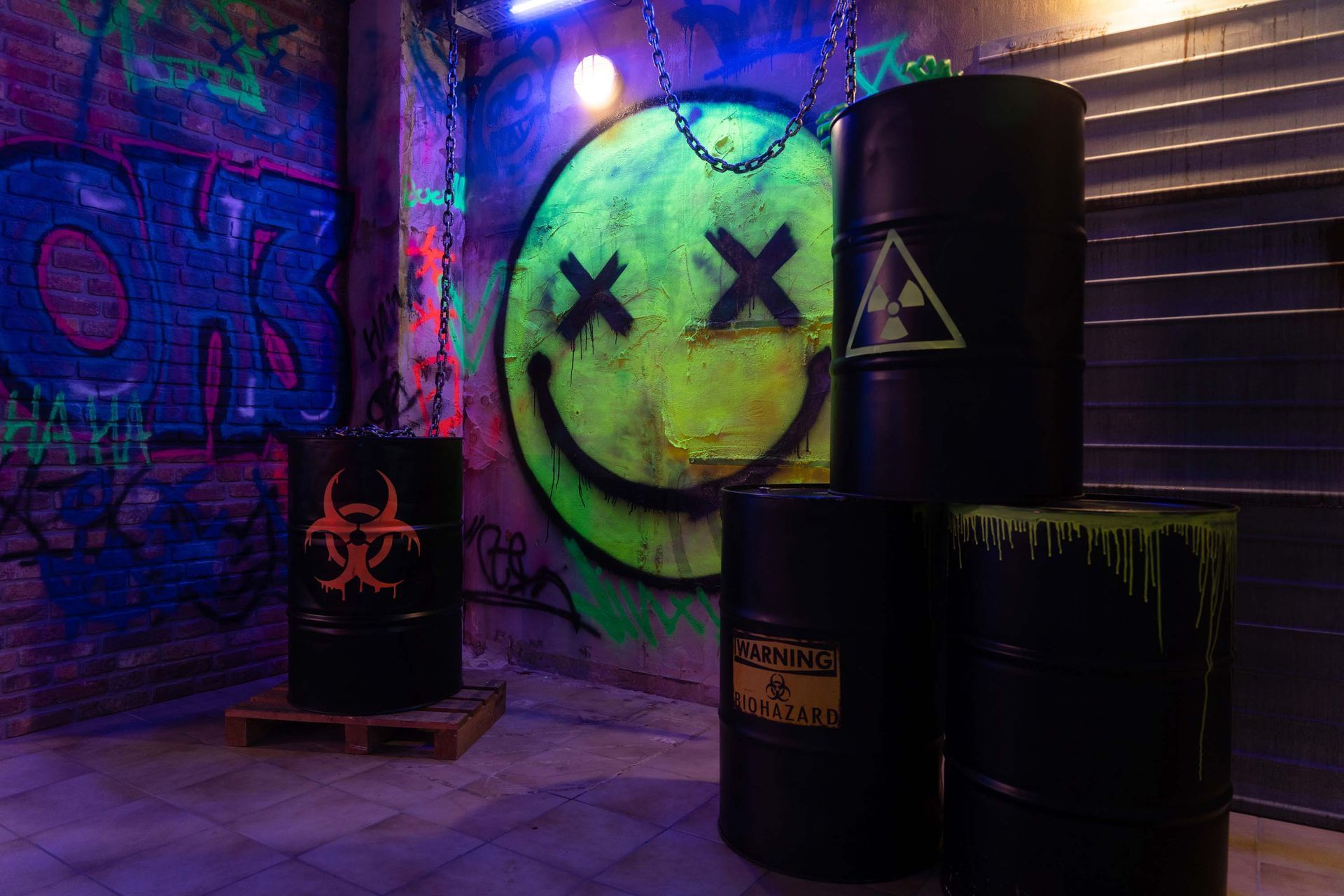 UV-leuchtendes Graffiti mit Smiley und Biohazard-Fässern in bunter Neonbeleuchtung