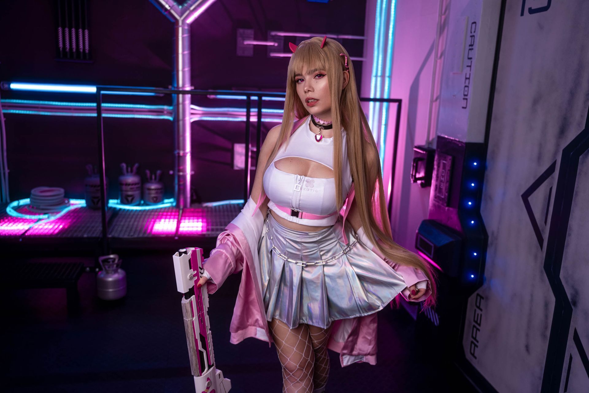 Cosplayerin mit langen blonden Haaren in futuristischem weiß-pinkem Outfit bei Neonlicht