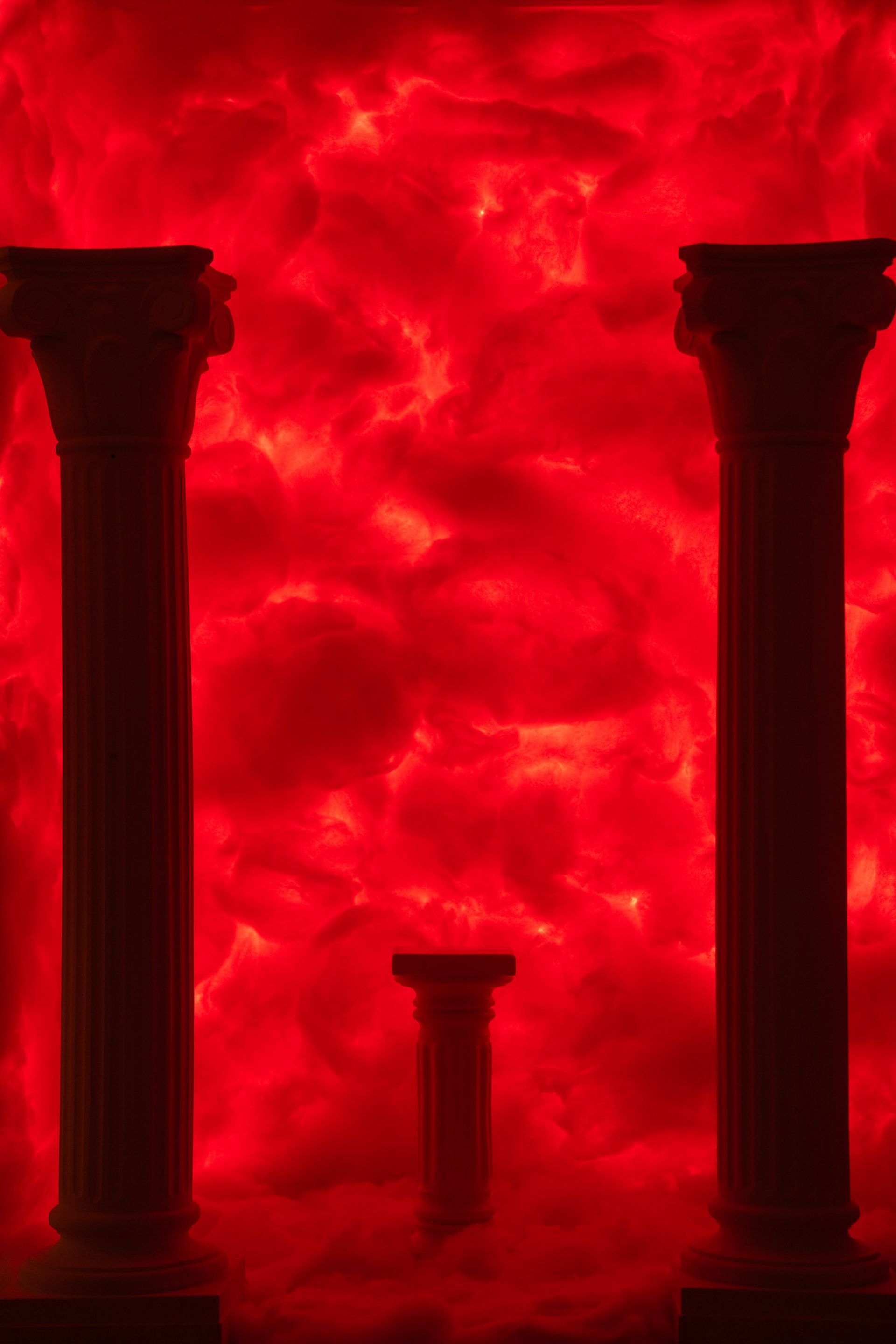 Dramatischer roter Raum mit Säulen und intensiver Wolkenbeleuchtung – leidenschaftliche und kraftvolle Kulisse.