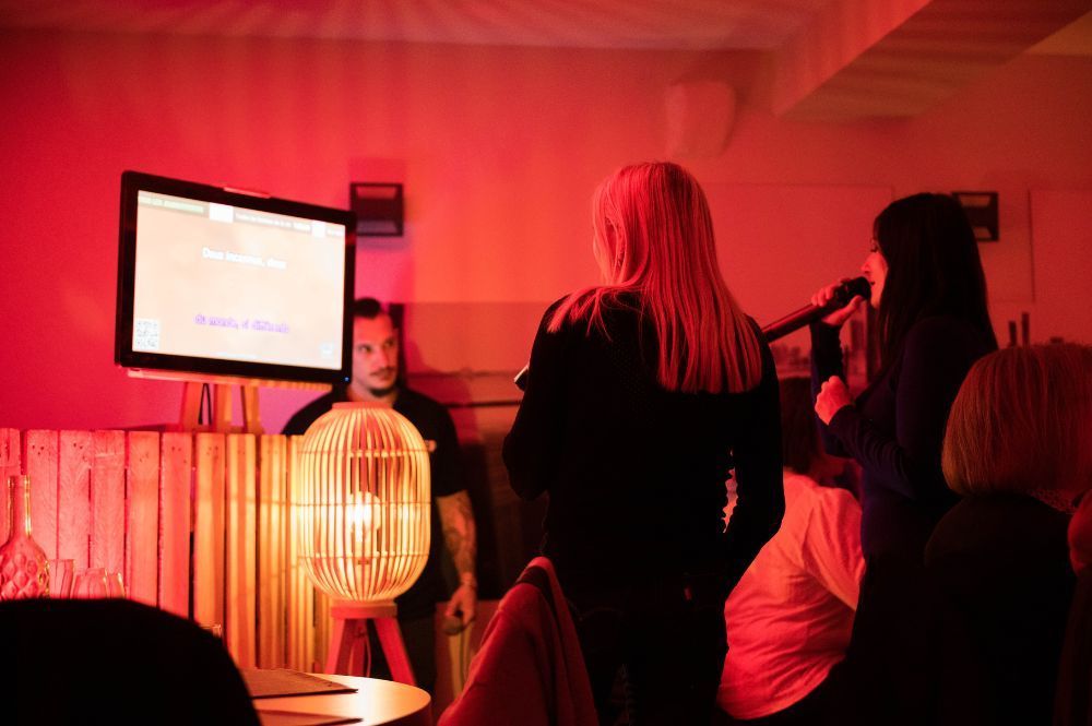 Deux personnes chantent devant un écran de karaoké dans un restaurant
