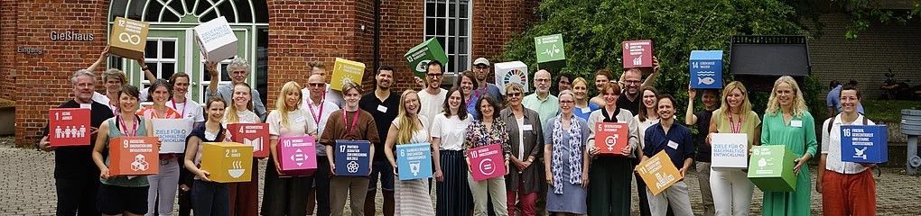 Das Bild zeigt viele Menschen mit Würfeln, auf denen die 17 Sustainable Development Goals abgebildet sind.