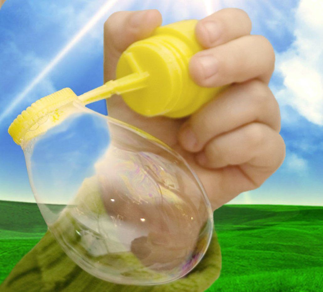 A hand holding a small bubble wand. There is a bubble forming, but not yet left the wand.