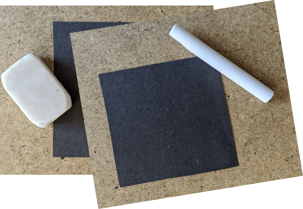 A picture showing some black paper, chalk and an eraser.