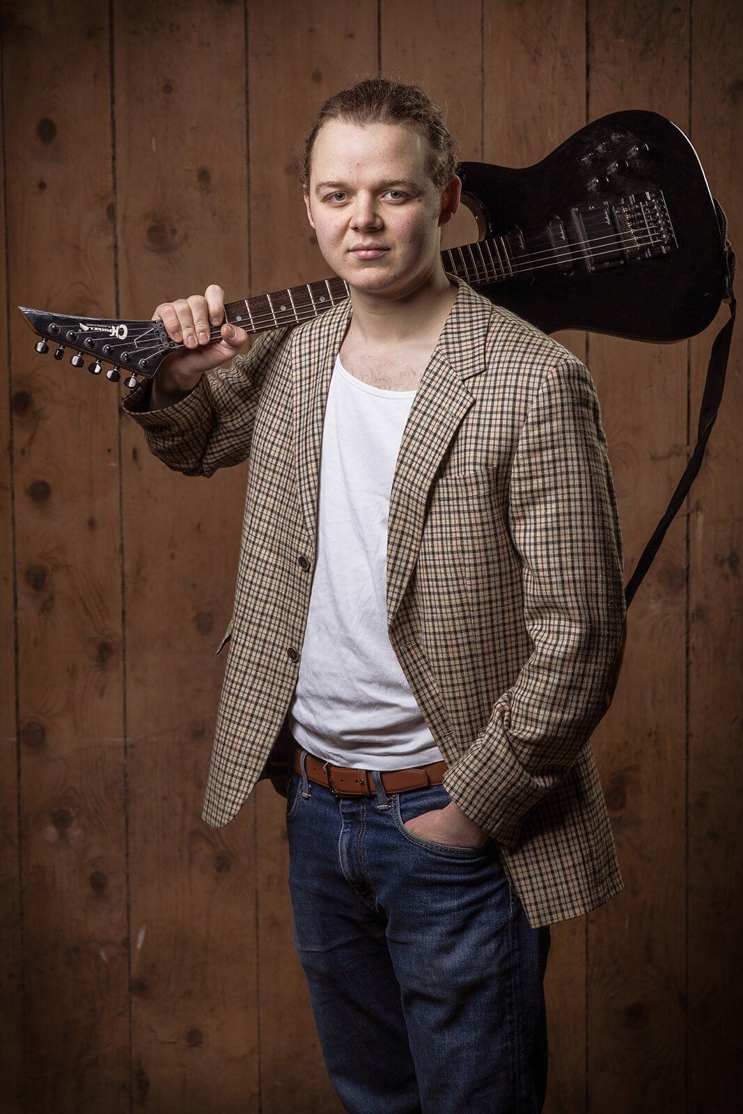 Gitarrist Georg mit Gitarre Portrait ab Knie von Gitarrist Georg mit Gitarre vor Holzwand