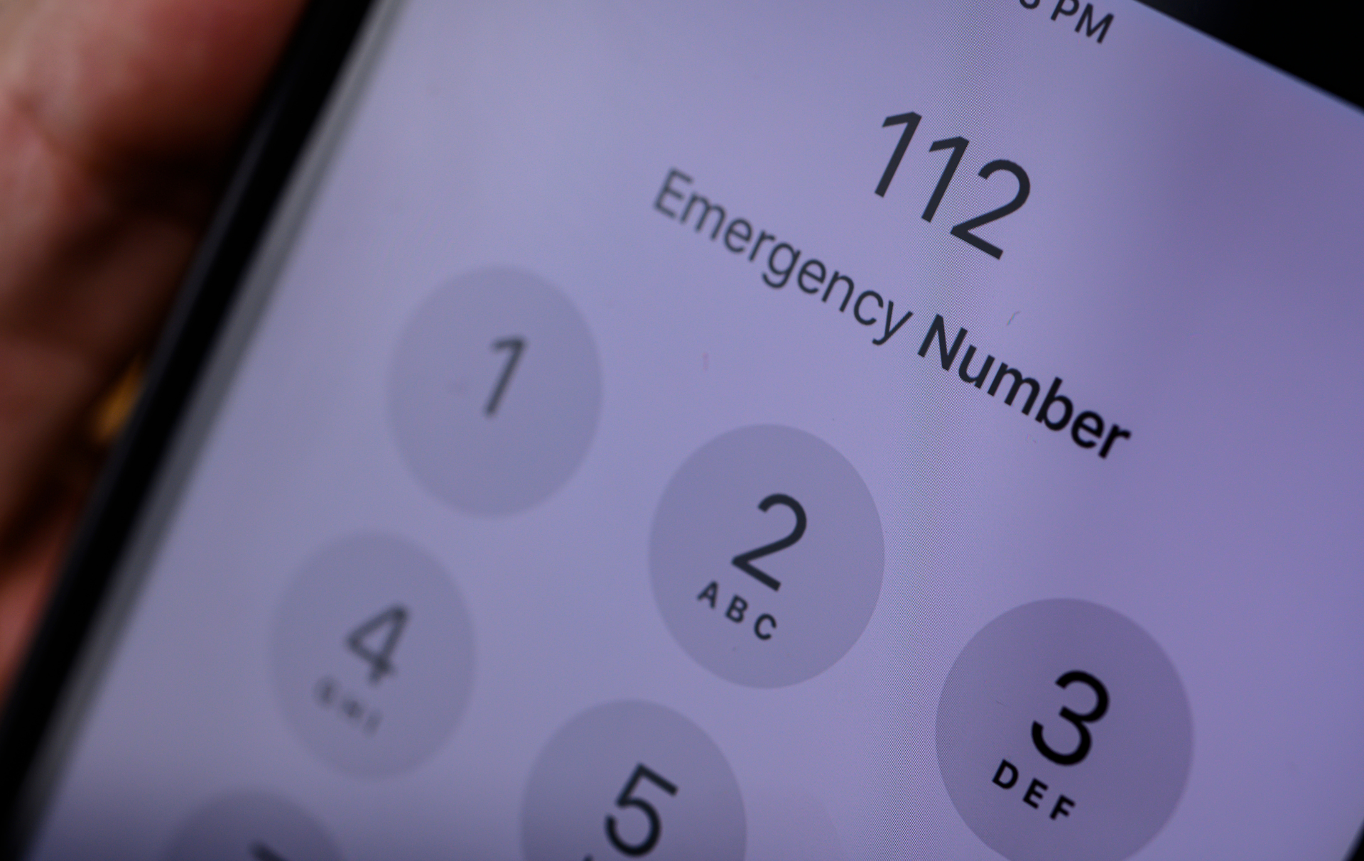 A phone with a call waiting that shows '112 - Emergency Number' on the screen