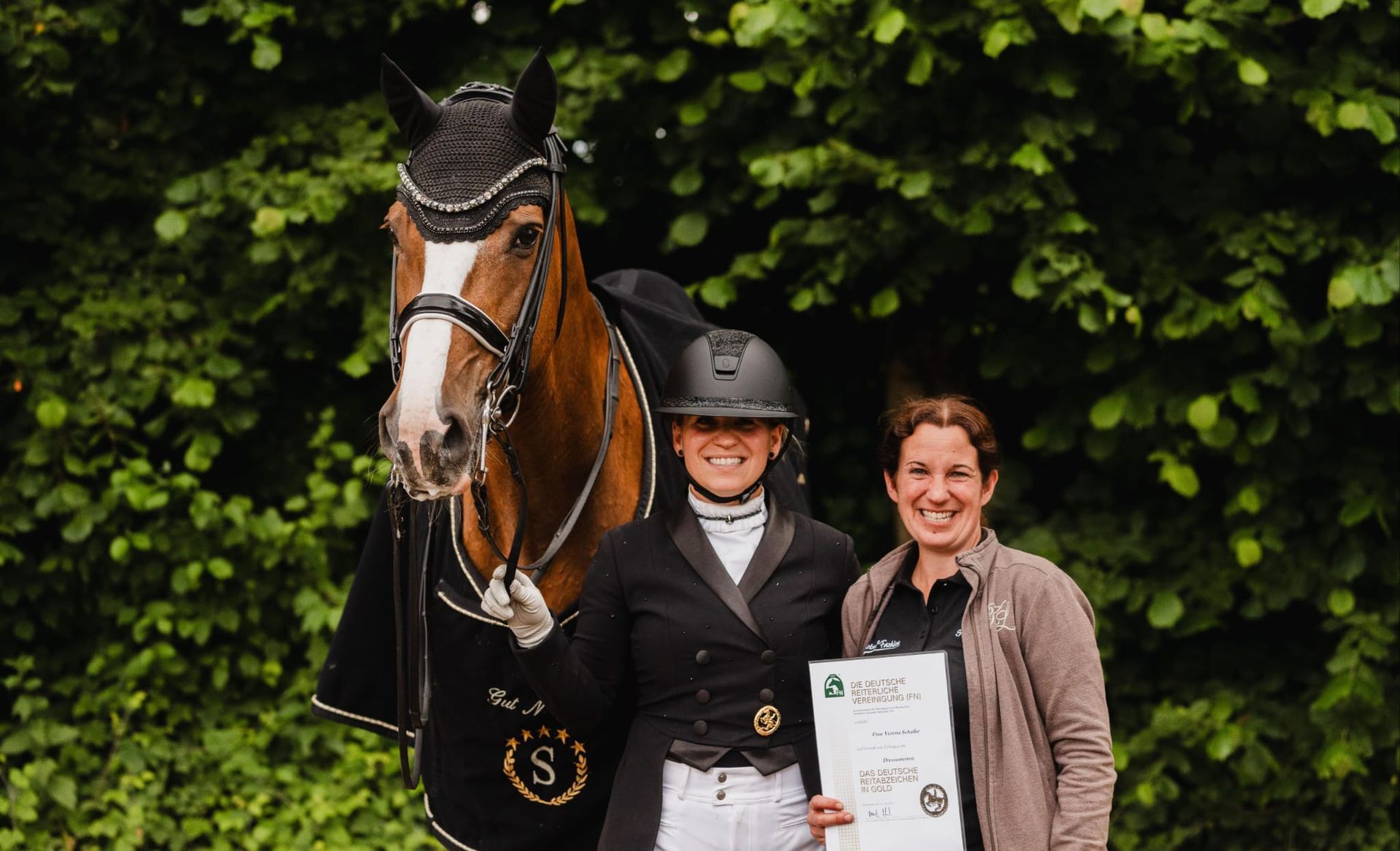 Verena Schalke und Schwester mit Pferd und bestickter Abschwitzdecke zum goldenen Reitabzeichen