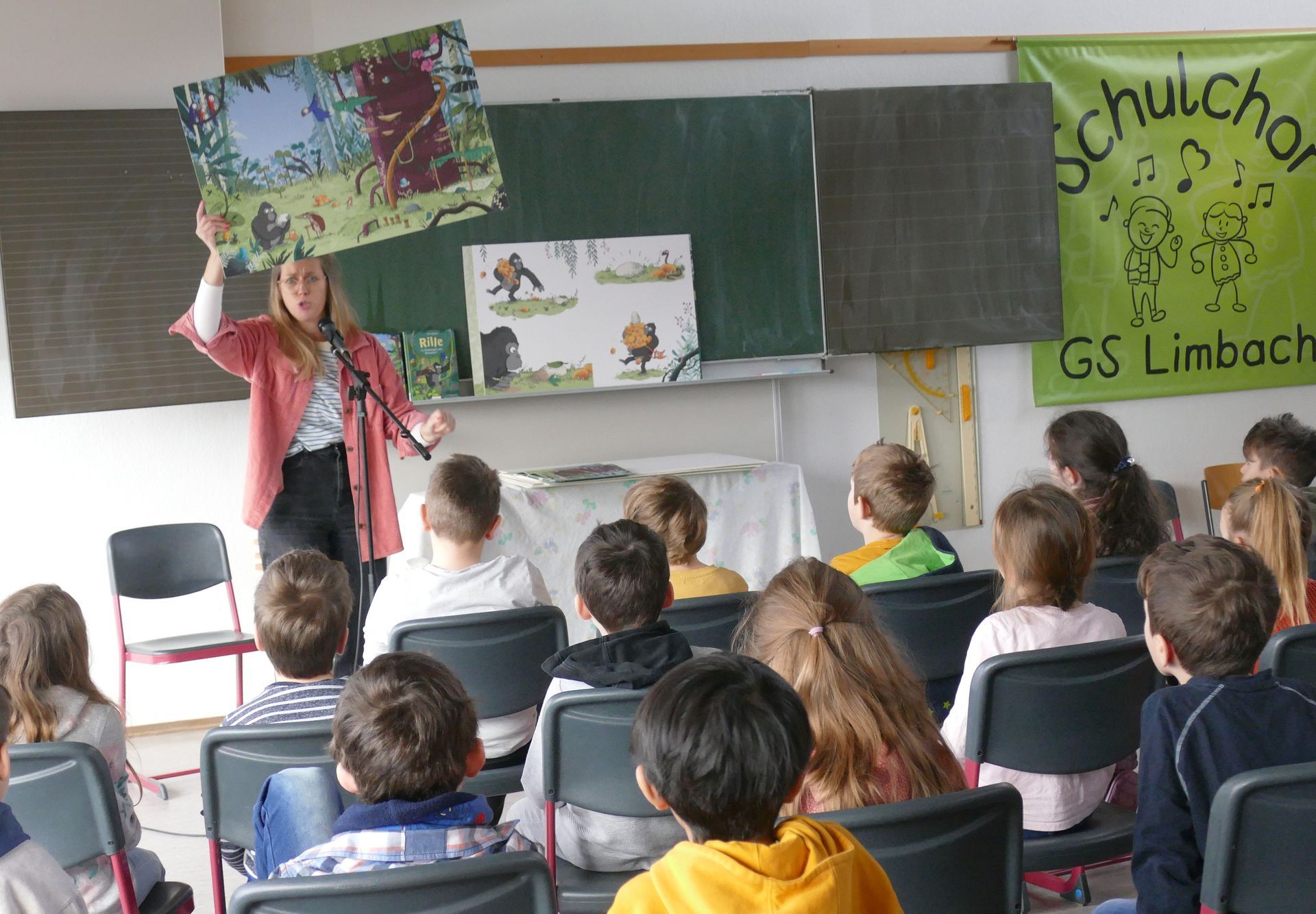 Wann ist bald? Jubiläums-Aktion der Bürgerstiftung förderte Lesen und Lesekompetenz bei Zweitklässlern mit einwöchiger Lesereise durch 20 Schulen Laudenberg/Schollbrunn. (ub) Das Programm ist ambitioniert und bestens organisiert. Eine Woche lang tourt ein Lese-Team der Bürgerstiftung Mosbach jeden Tag zu vier verschiedenen Schulen, von Mudau bis Billigheim, von Aglasterhausen bis Seckach.  Der Anlass liegt eigentlich schon ein bisschen zurück. Ein Zehnjahresjubiläum sollte gebührend begangen werden, musste aber Corona-bedingt verschoben werden. Seit nunmehr zwölf Jahren nämlich hat sich die Bürgerstiftung Leseförderung auf die Fahnen, besser: Buchdeckel geschrieben. Mit Prominenten-Vorleseaktionen, Buchgutscheinen, Leseaktionen in Schulen, Lesepaten, einem Lesebären, Lesetüten, viel persönlichem ehrenamtlichem Engagement und nicht zuletzt erheblichen Geldbeträgen der Stiftung wurde und wird viel dafür getan, das Lesen zu fördern und Lesekompetenz zu stärken. „Zum Jubiläum aber sollte es was Besonderes sein“, berichten Christel Mayer und Patricia Spitzer. Letztere ist im Vorstand der Bürgerstiftung, erstere einst Grundschullehrerin und –leiterin und von Anfang an das Gesicht allen Leseförder-Engagements der Stiftung. Das Besondere ist die Kinderbuchautorin Fee Krämer, die für eine Lesereise gewonnen wurde. Auch die musste einmal verschoben werden, doch nun war es für knapp 800 Schülerinnen und Schüler der zweiten Klasse endlich soweit. Der Titel ihres Buches „Wann ist bald?“ hätte zur Geschichte der Tournee kaum besser passen können. „Wann ist für dich bald?“ Auf die Frage bekam Krämer in der Grundschule Laudenberg von ihren jungen Zuhörern eine Zeitspanne von zehn Minuten bis zehn Jahre genannt. „Wenn man was macht, was einem selbst und anderen Spaß macht, dann geht die Zeit schneller rum“, wusste ein Mädchen in der Winterhauch-Schule in Schollbrunn – der zweiten Station am dritten Tag der Lesereise - auf die Frage nach dem Vergehen von Zeit zu sagen und hatte damit den Kern des Kinderbuches getroffen. Es handelt vom Gorilla Rille, seinen Dschungel-Freunden und der Geduld. Fee Krämer las nicht nur vor, sondern hauchte den Figuren Leben ein, zeigte die Illustrationen des Buches (von Nikolai Renger) mal als große Tafeln, mal in digitaler Form auf dem Klassenbildschirm, vor allem aber bezog sie ihre junge Hörerschaft in das Geschehen immer wieder ein; schließlich handelt es sich um ein „Mitmach-Buch“.  Mitmacher der Bürgerstiftungs-Initiative sind die 20 Grundschulen, ihre jeweiligen Leitungen und Lehrerinnen, die das tourende Trio nur zu gern empfingen. Sowohl Rektor Thorsten Schwab (Laudenberg) als auch Rektor Ulrich Schöpwinkel (Scholbrunn) ließen es sich nicht nehmen, Exemplare des Vorlesebuches für die eigenen Kinder von Fee Krämer signieren zu lassen. Für die Kinder, die es wollten, tat die Autorin es ebenfalls am Ende ihrer jeweiligen Vorlese- und Mitmachstunde. Denn das gehört zur aktuellen Lese-Initiative der Bürgerstiftung dazu, dass jedes Kind ein Rille-Buch erhielt. Auf den dazugehörigen Taschen steht, warum man sich in Sachen Leseförderung so engagiert: „Sprache ist der Schlüssel zur Welt.“ Die Kosten für knapp 800 Bücher und die Honorarkosten für die Autorin gehen auf das Konto der Bürgerstiftung beziehungsweise von diesem weg. Mit rund 14 000 Euro hat sich die Stiftung anlässlich der Jubiläumsaktion dieses Mal besonders ins Zeug gelegt. Zur Unterstützung der lesefördernden Sache trug auch Kindler’s Buchhandlung bei, indem diese ihre Ferienwohnung, in der die aus Berlin angereiste Autorin während ihrer Odenwald-Tournee wohnte, kostenlos zur Verfügung stellte. Ob es nicht langweilig sei, 20 Mal hintereinander die gleiche Lesestunde zu absolvieren, wurde Fee Krämer gefragt. „Gleich? Nein!“ lautete die Antwort, „es ist doch jedes Mal anders.“ Und auf die Frage an die Initiatorinnen, wann das nächste „Bald“, wann die nächste Lese-Aktion der Bürgerstiftung zu erwarten sei, nannten Patricia Spitzer und Christel Mayer die kommenden Zweitklässler des Schuljahres 2023/2024. „Da gibt es dann wieder Lesetüten.“   Nah dran war Kinderbuchautorin Fee Krämer bei ihren jungen Leserinnen und Lesern in den Schulklassen während ihrer Lesetour.