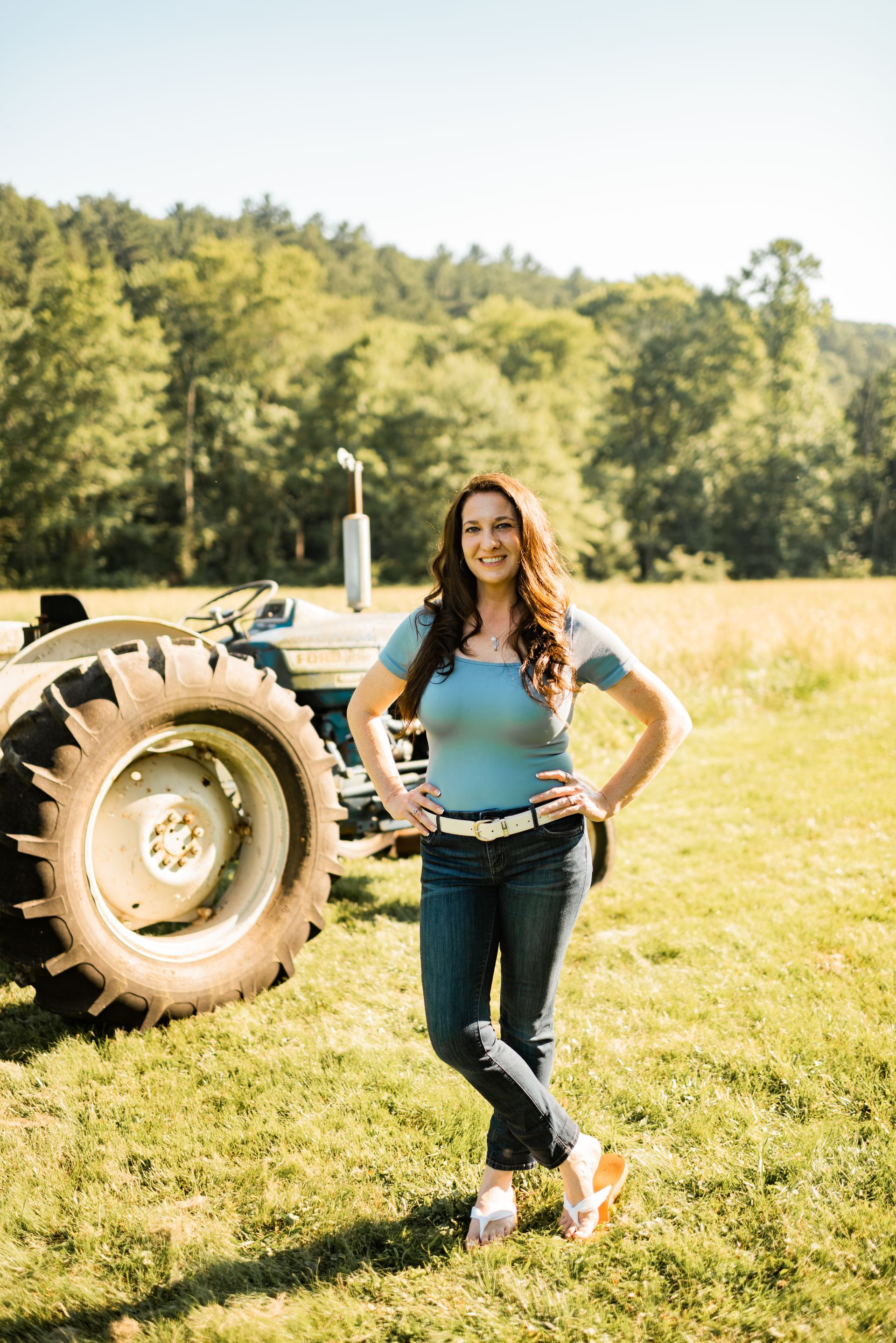 Shaunna Huhnke standing by a blue tractor, owner of Farmer Girl Web Design