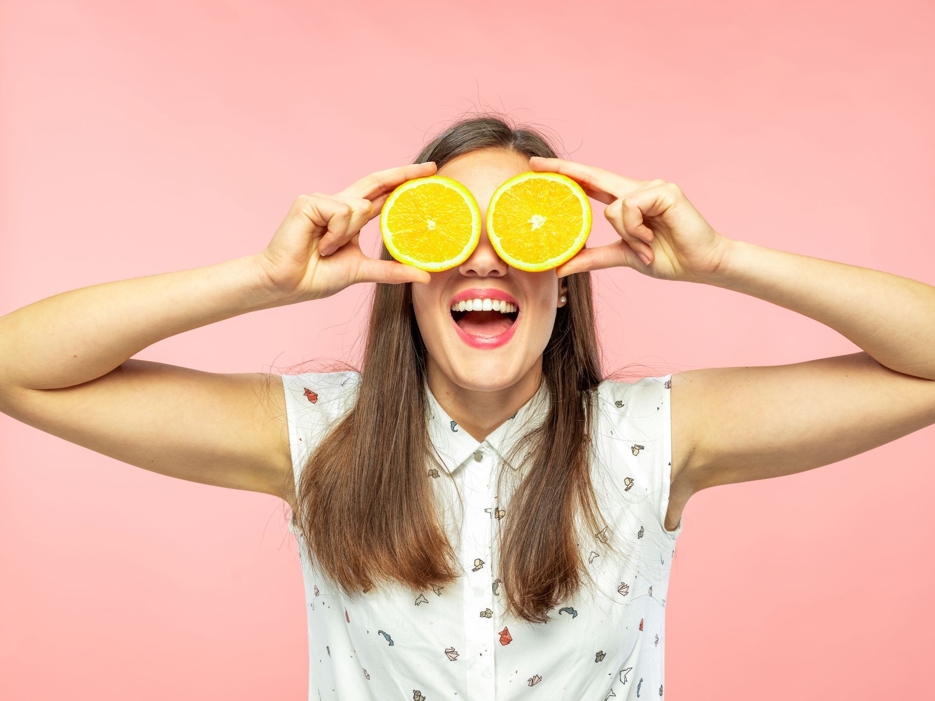 Woman holding oranges in front of eyes to highlight essential nutrition building blocks