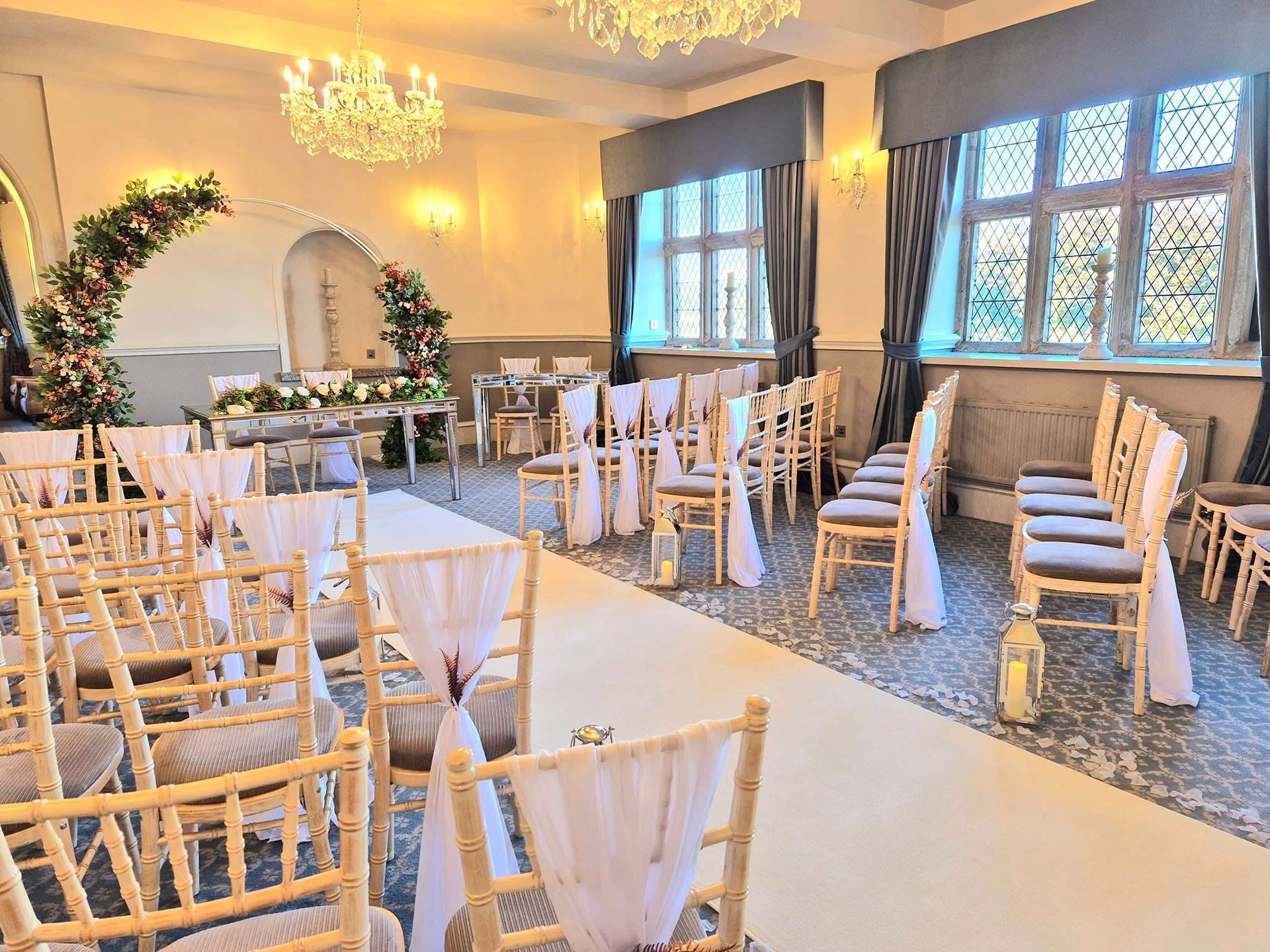Wedding ceremony room setup with moongate arch and white chiffon chair drapes.
