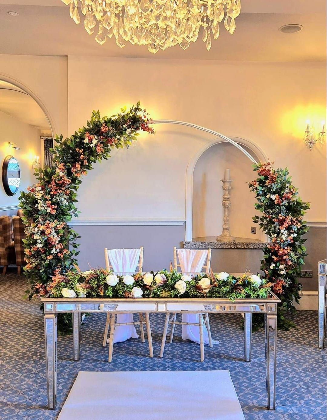 Burnt orange and green foliage moongate arch with ceremony table garland.