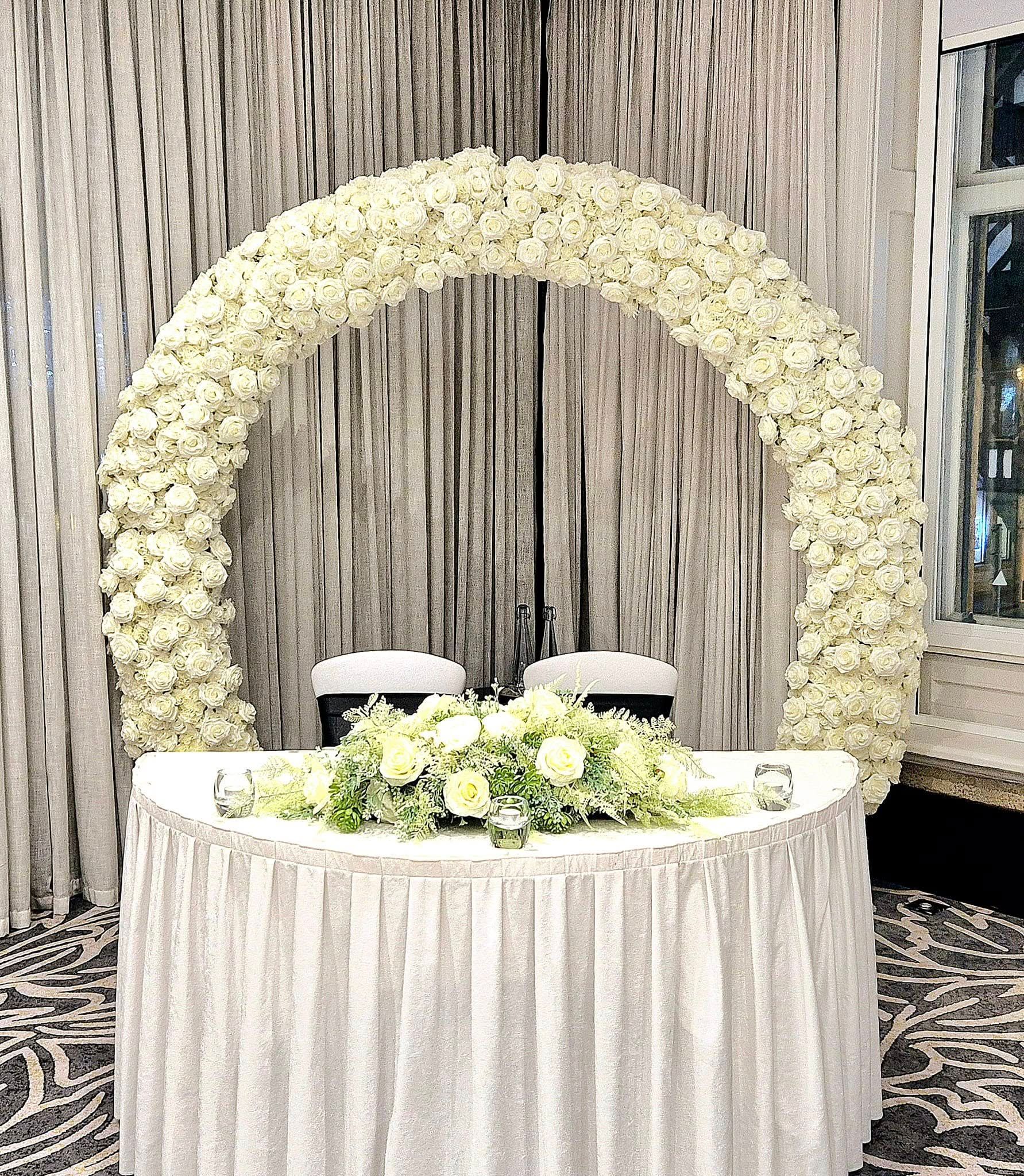 White luxe moongate arch filled with roses.