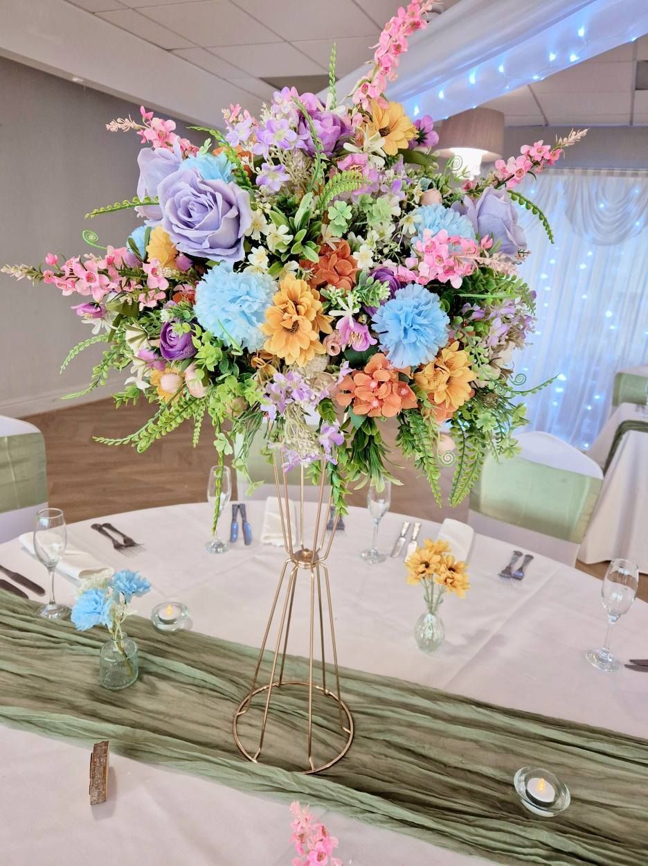 Vibrant mixed flower colour centrepiece on gold stand.