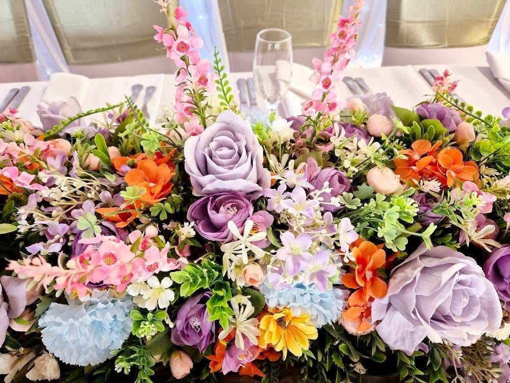 Vibrant mixed flower colour centrepiece on gold stand.