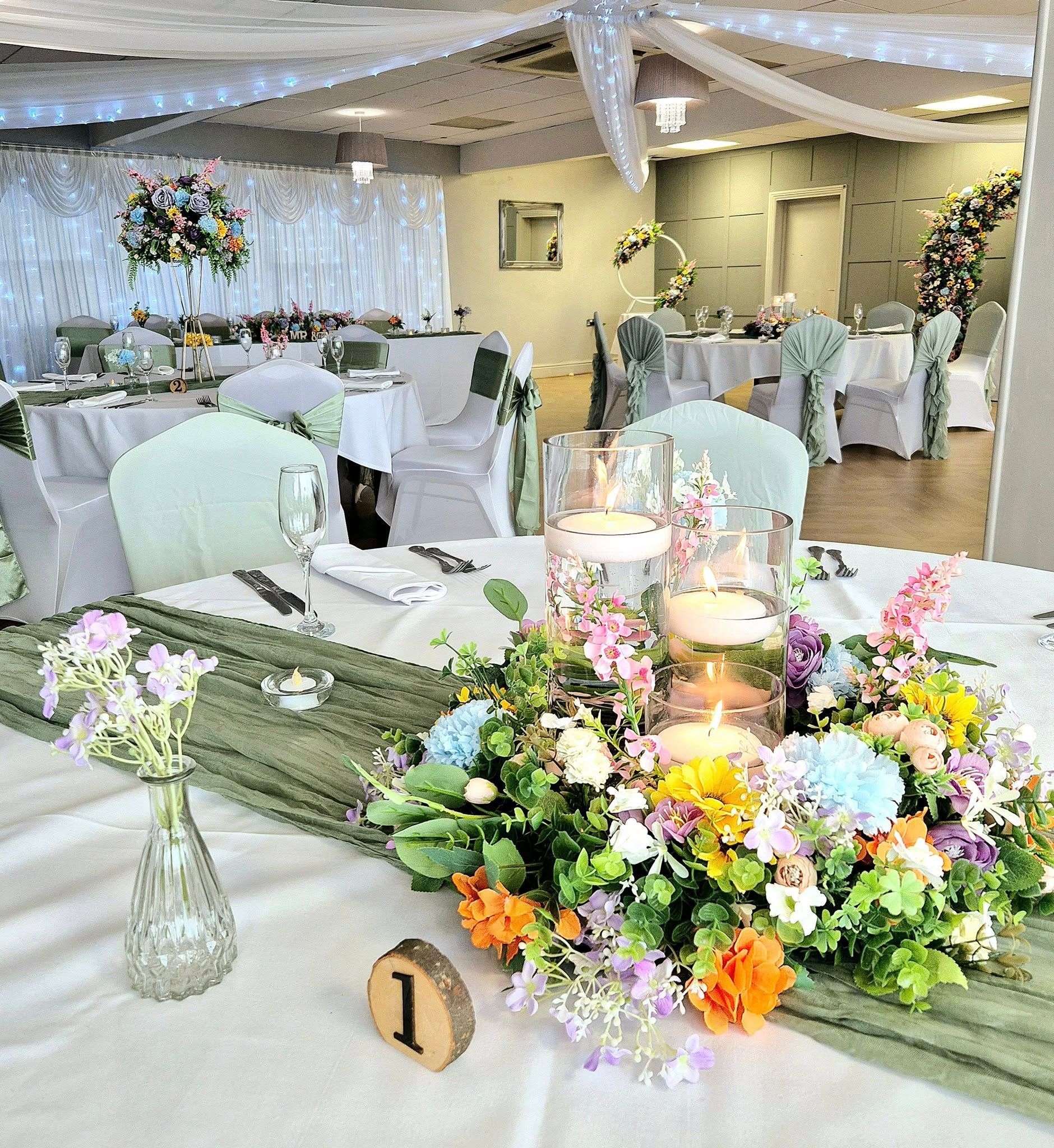 Vibrant colour floral hoop surrounding cylinder vases with floating candles to create a beautiful centrepiece