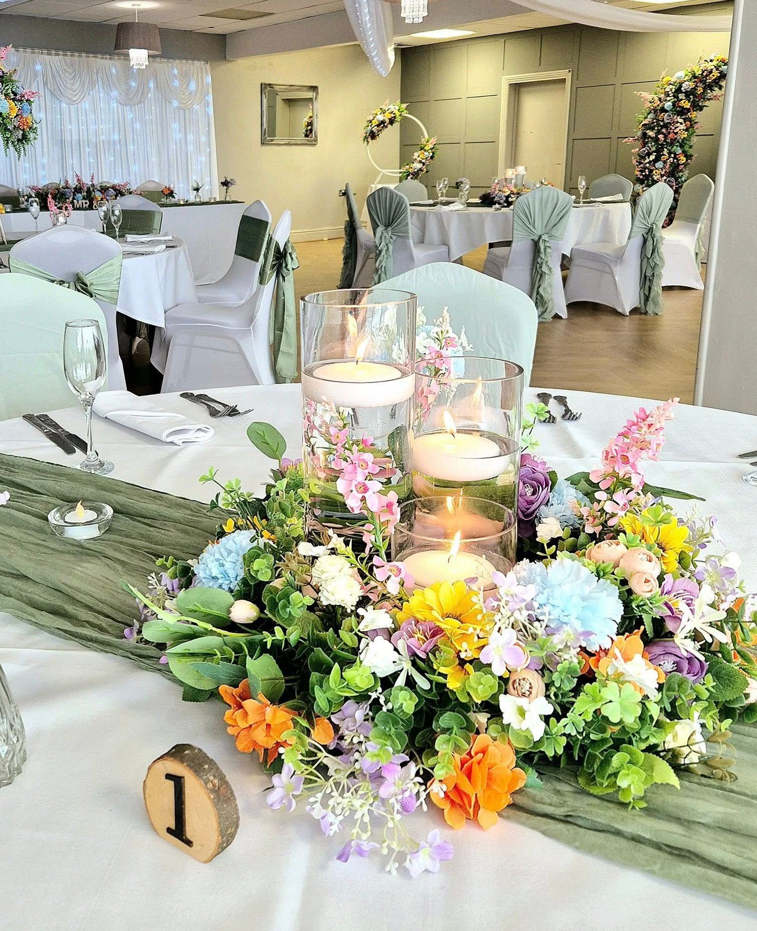 Burnt orange and green foliage moongate arch with ceremony table garland.