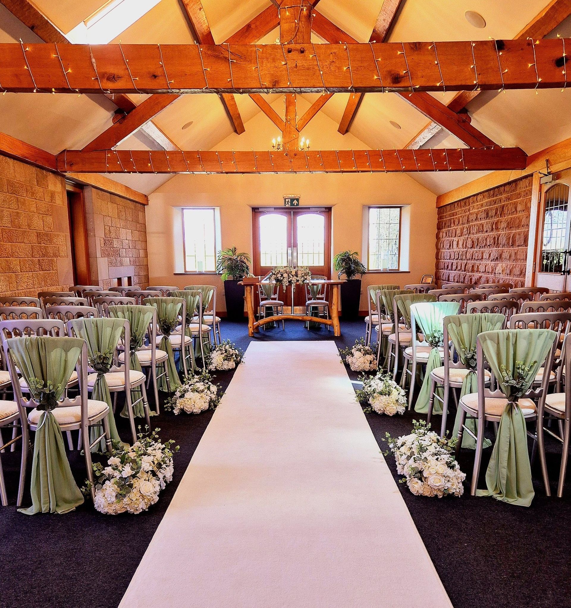 Wedding ceremony setup with sage green chiffon drapes and flower runners down the aisle