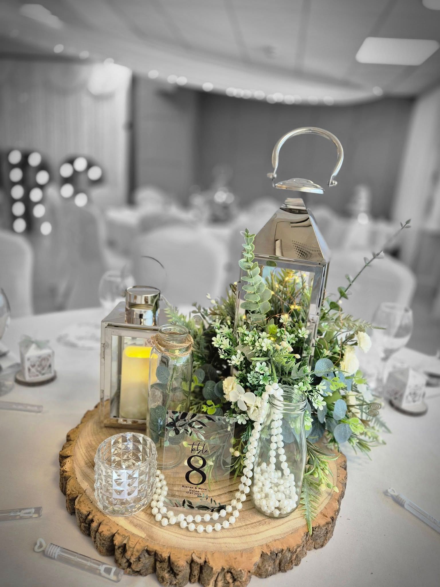 Rustic lantern wedding centerpiece with silver lanterns and white flowers on wood slice base