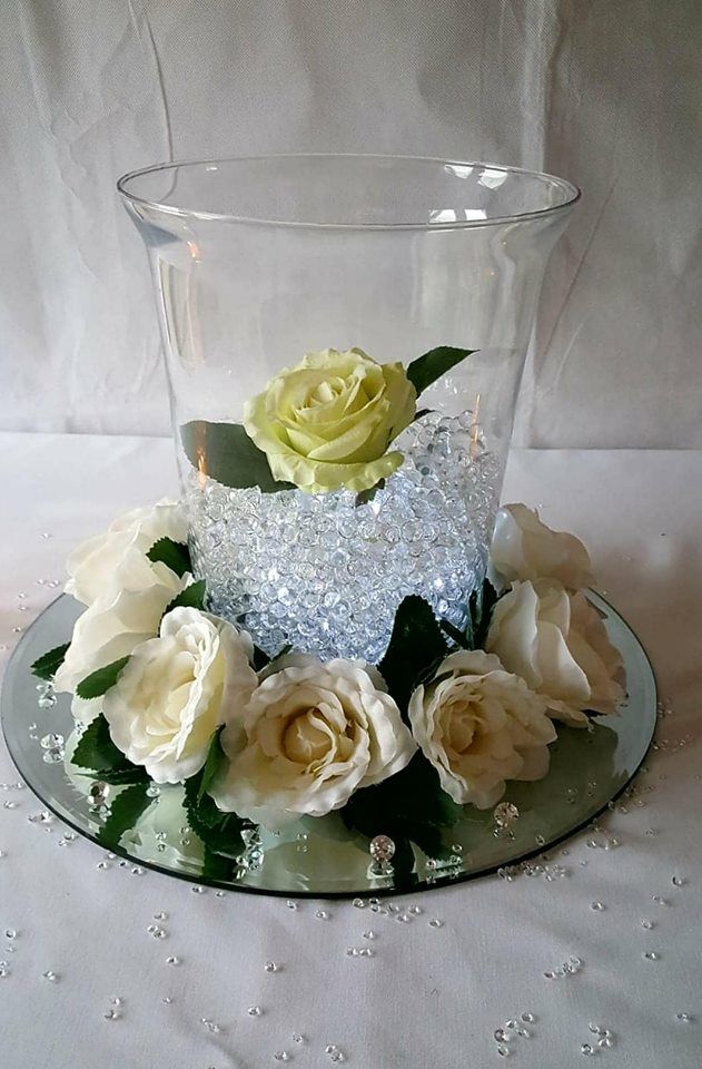 Close up of a hurricane vase centrepiece with flowers around the outside