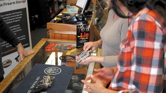 Customers at the counter looking at guns