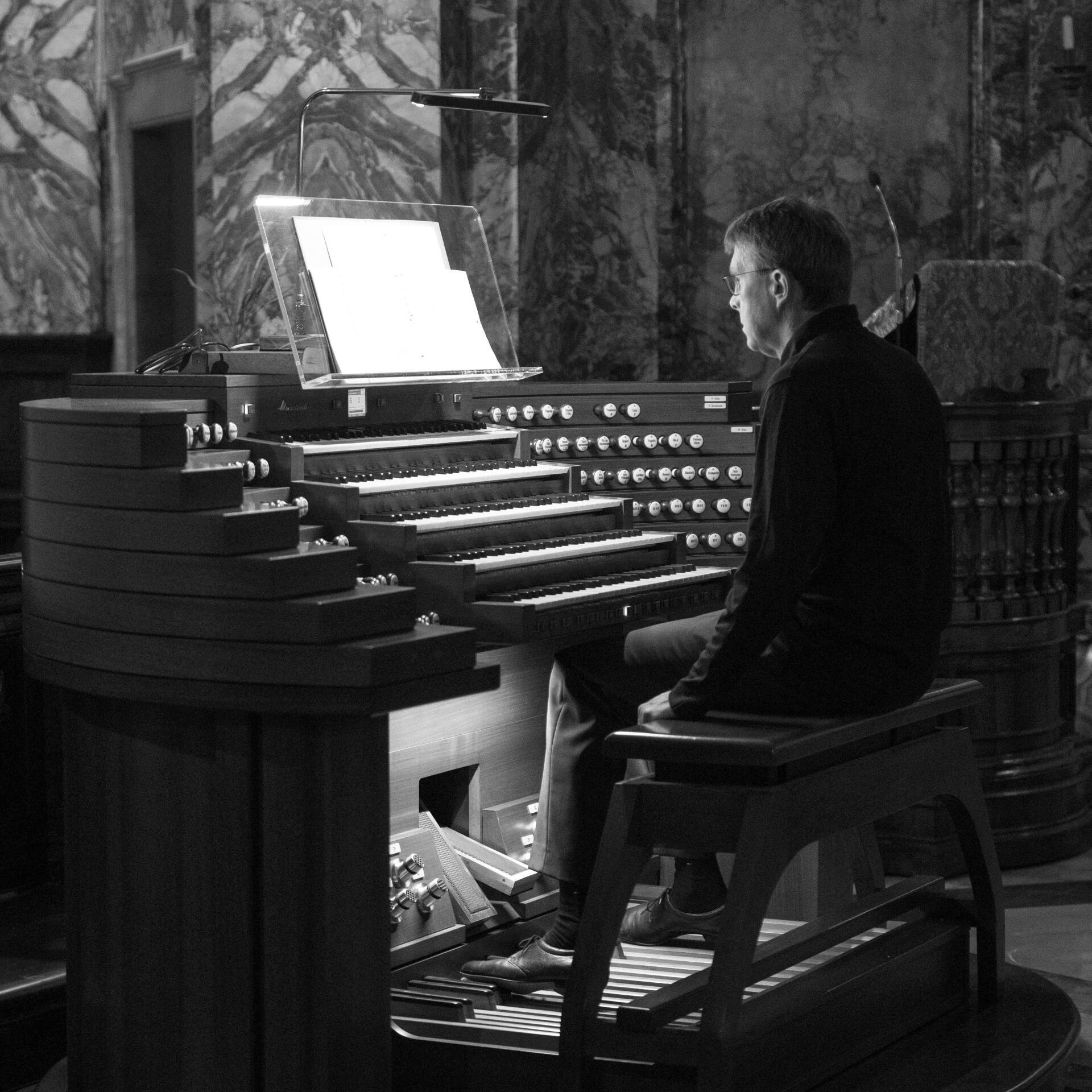 Bild in schwarz-weiß, Jürgen Sonnentheil sitzt an der Orgel
