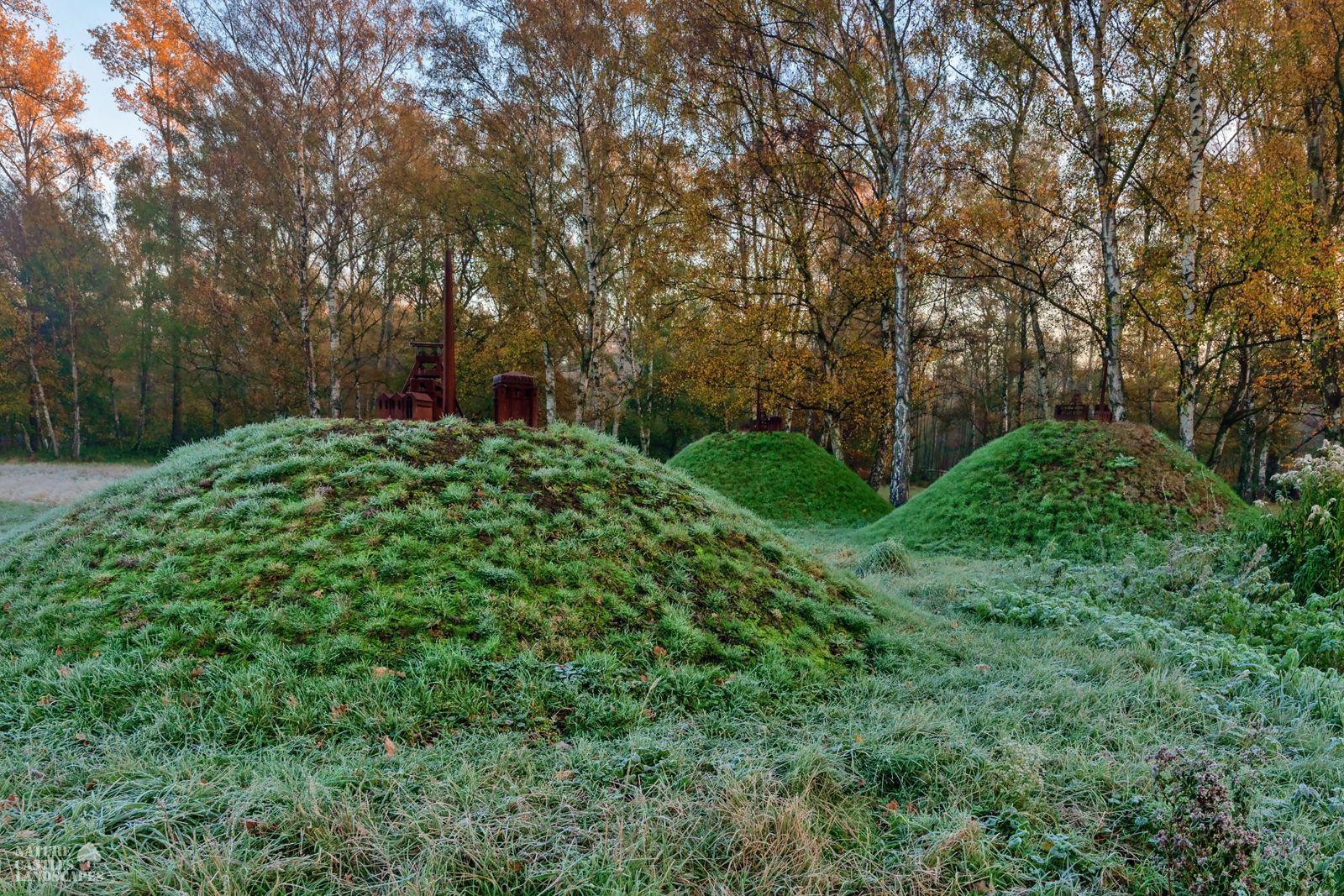 three metal models of a colliery at sunset