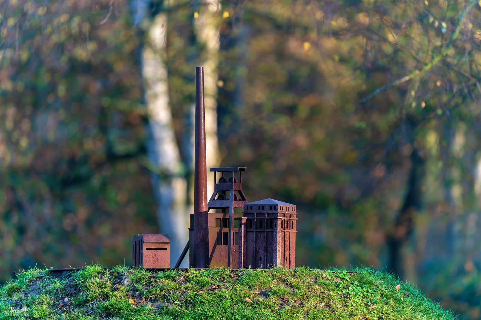 rusty metal model of a colliery in front of a forest
