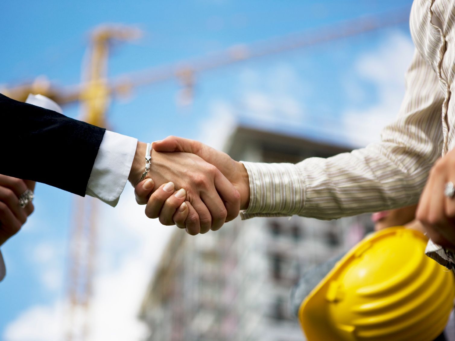 Two Hands Shaking In Front of a Construction Project