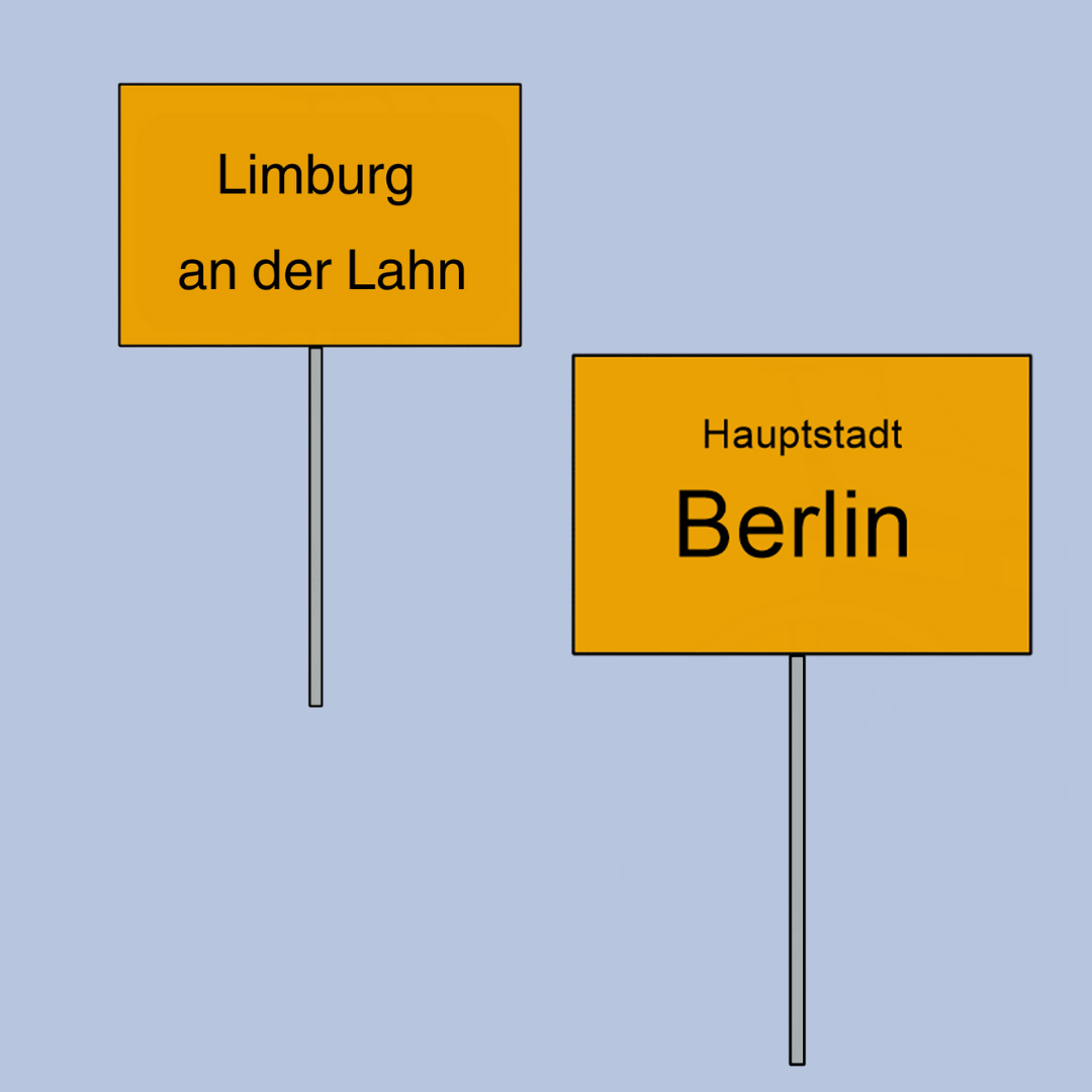 Zwei gelbe Ortsschilder: links steht „Limburg an der Lahn“, rechts steht „Hauptstadt Berlin“.