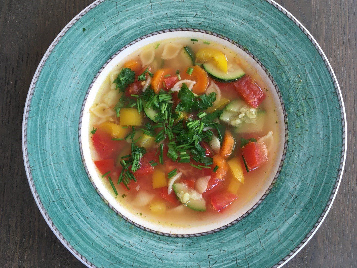Teller mit klarer Suppe mit viel Gemüse und Nudeln