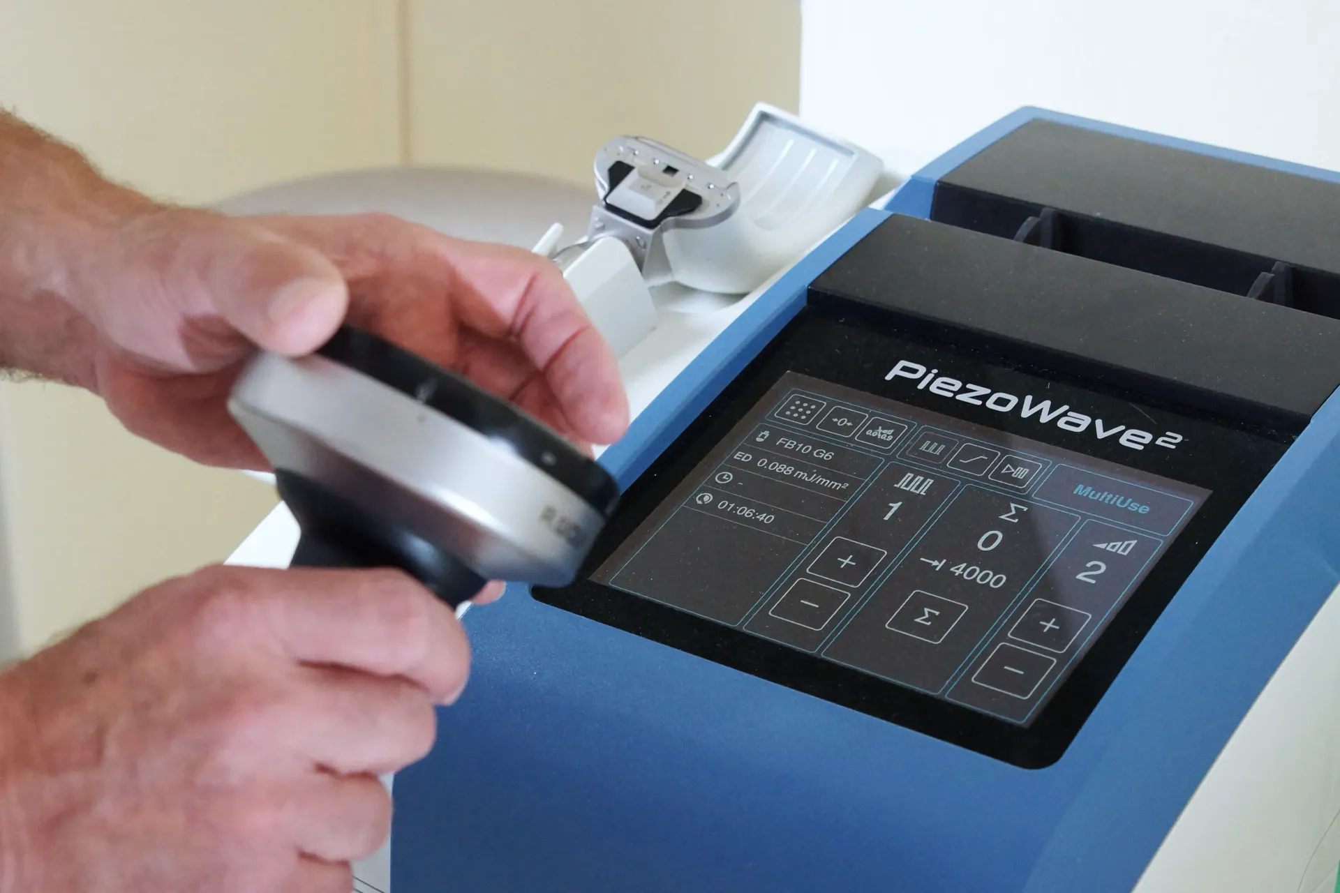 Ein Gerät das PiezoWave heißt mit zwei Händen, die das an Handgerät halten