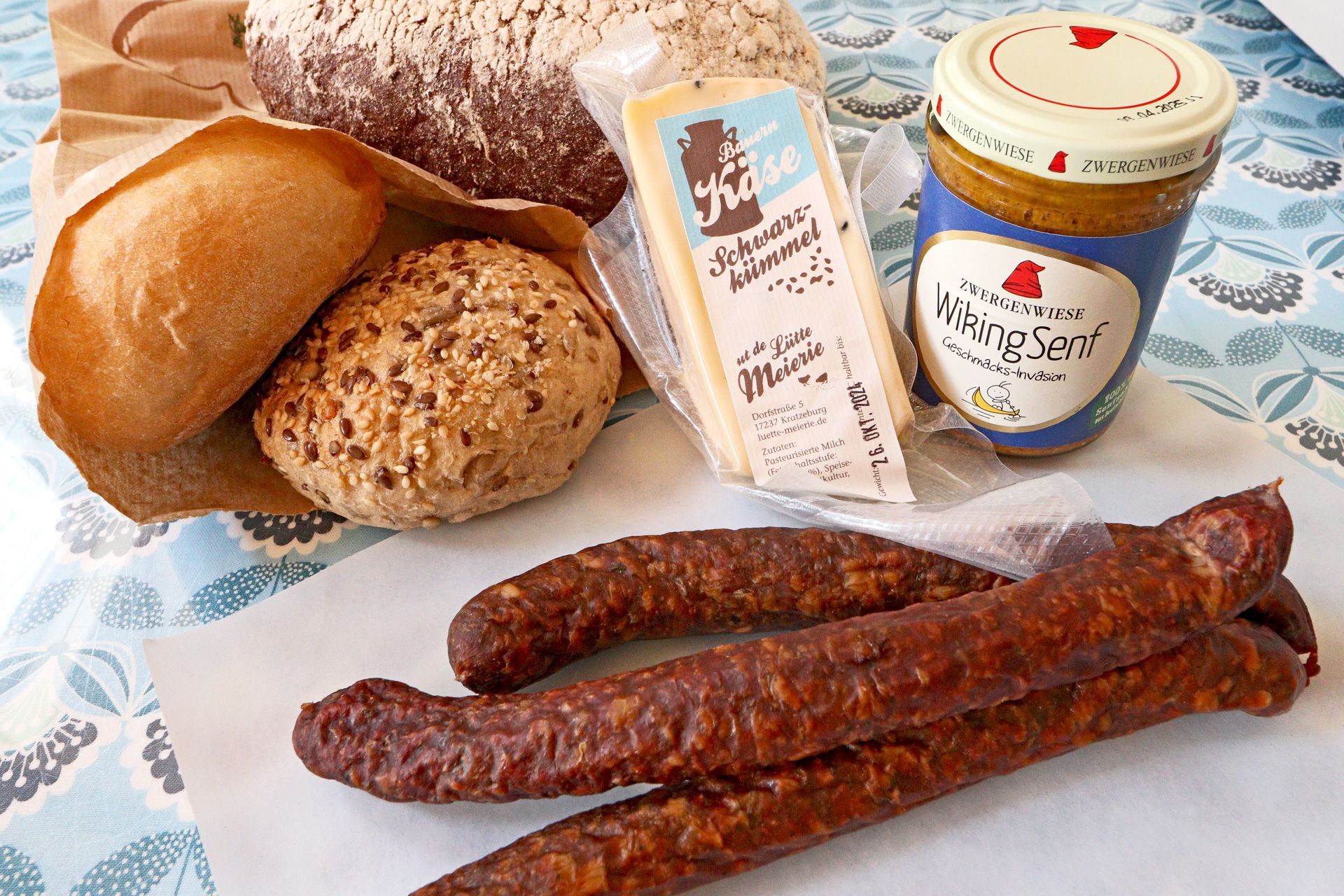 Brötchen, Brot, Käse, Senf und Knacker auf dem Tresen des Hofladens