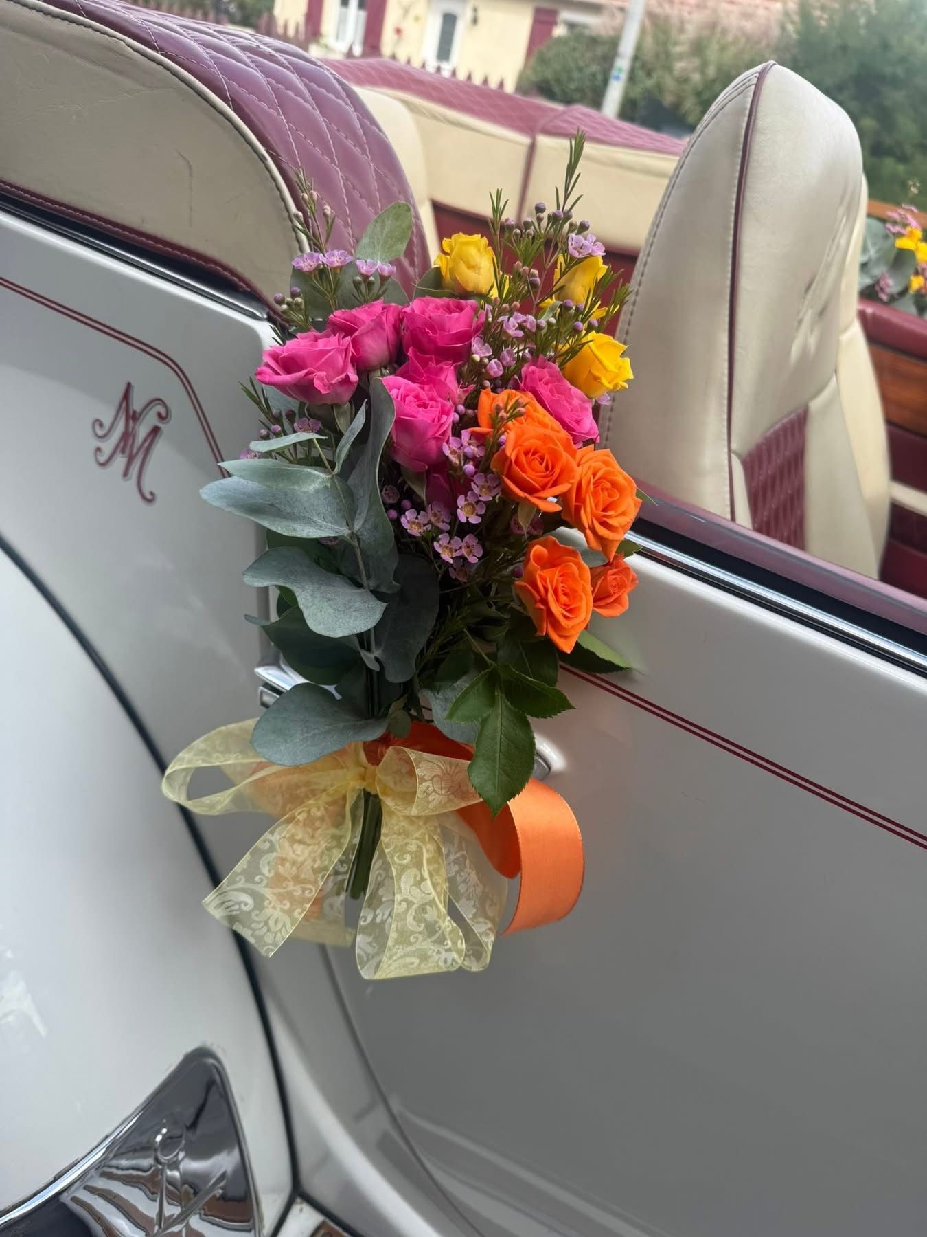 Fleurs colorées dans une voiture avec un nœud décoratif sur la porte.