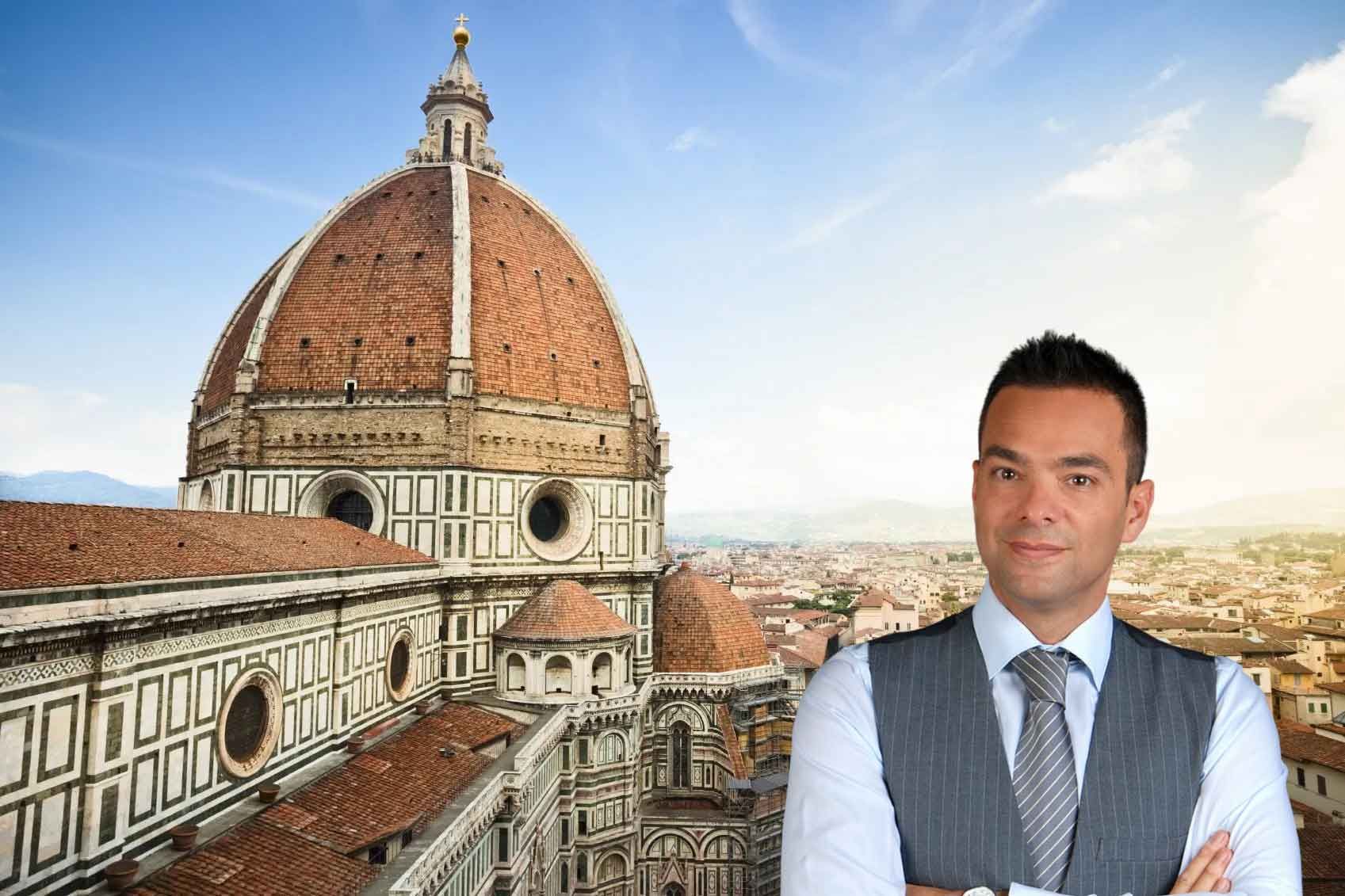 Ein Mann in Geschäftskleidung steht mit verschränkten Armen unter einem klaren Himmel vor der Kathedrale von Florenz mit ihrer ikonischen Kuppel und beratet den Kauf Immobilie in Italien