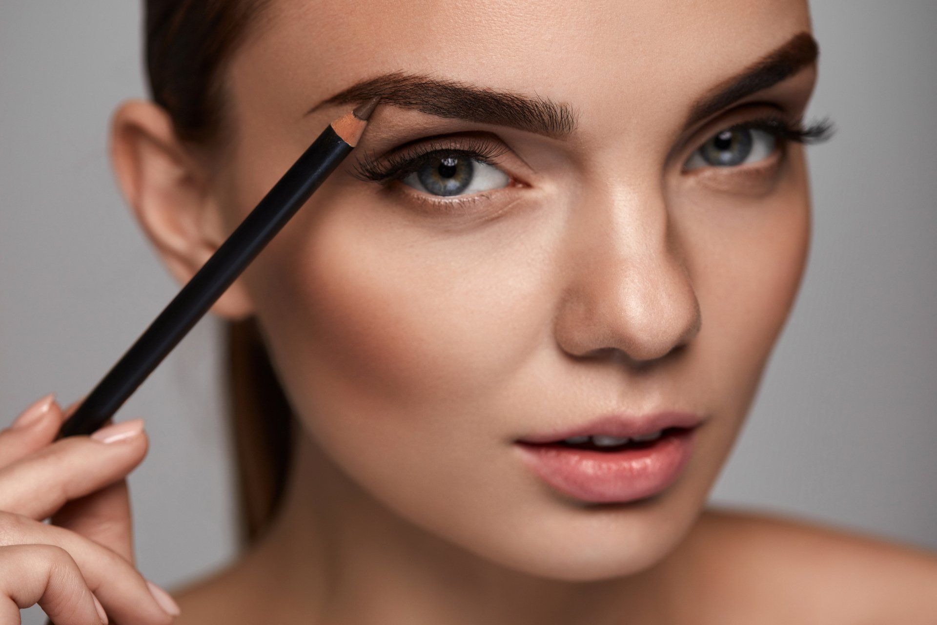 Woman pencilling in eyebrows
